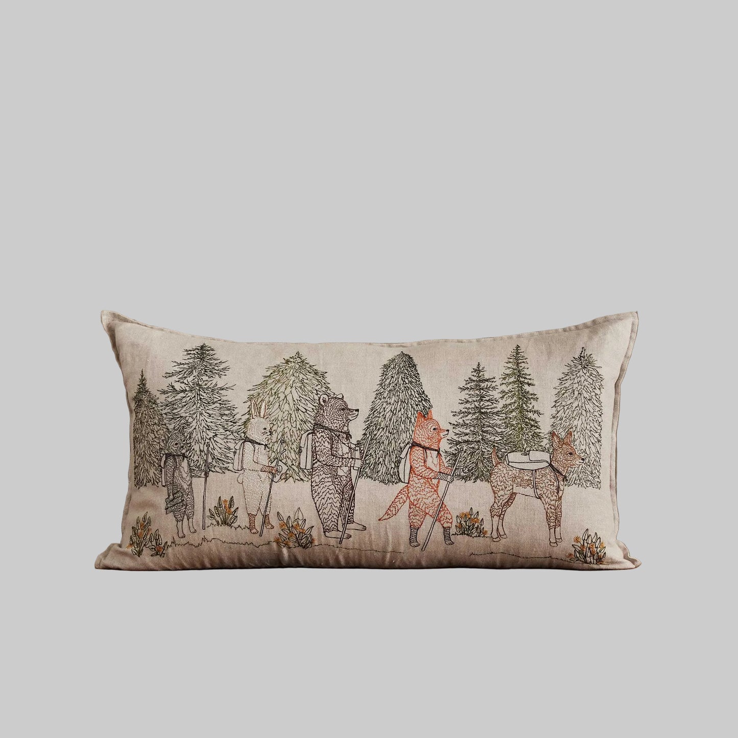 Coral and Tusk’s “Hikers” embroidered linen pillow featuring woodland friends trekking through the wilderness, measures 14” x 26”