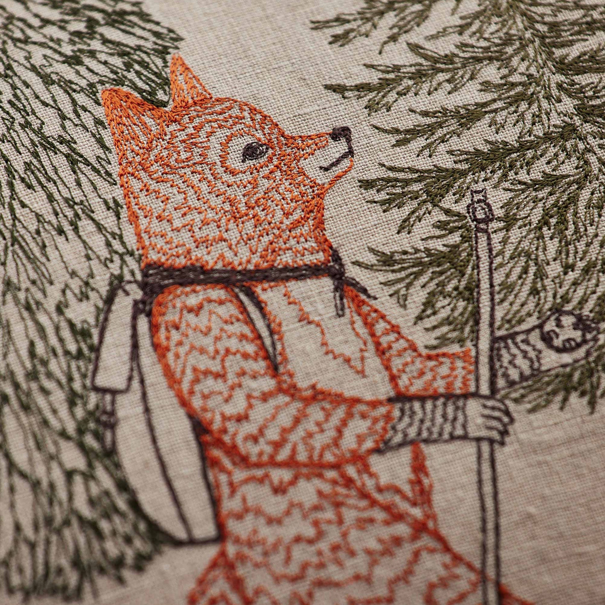 Coral and Tusk’s “Hikers” embroidered linen pillow featuring woodland friends trekking through the wilderness, measures 14” x 26”