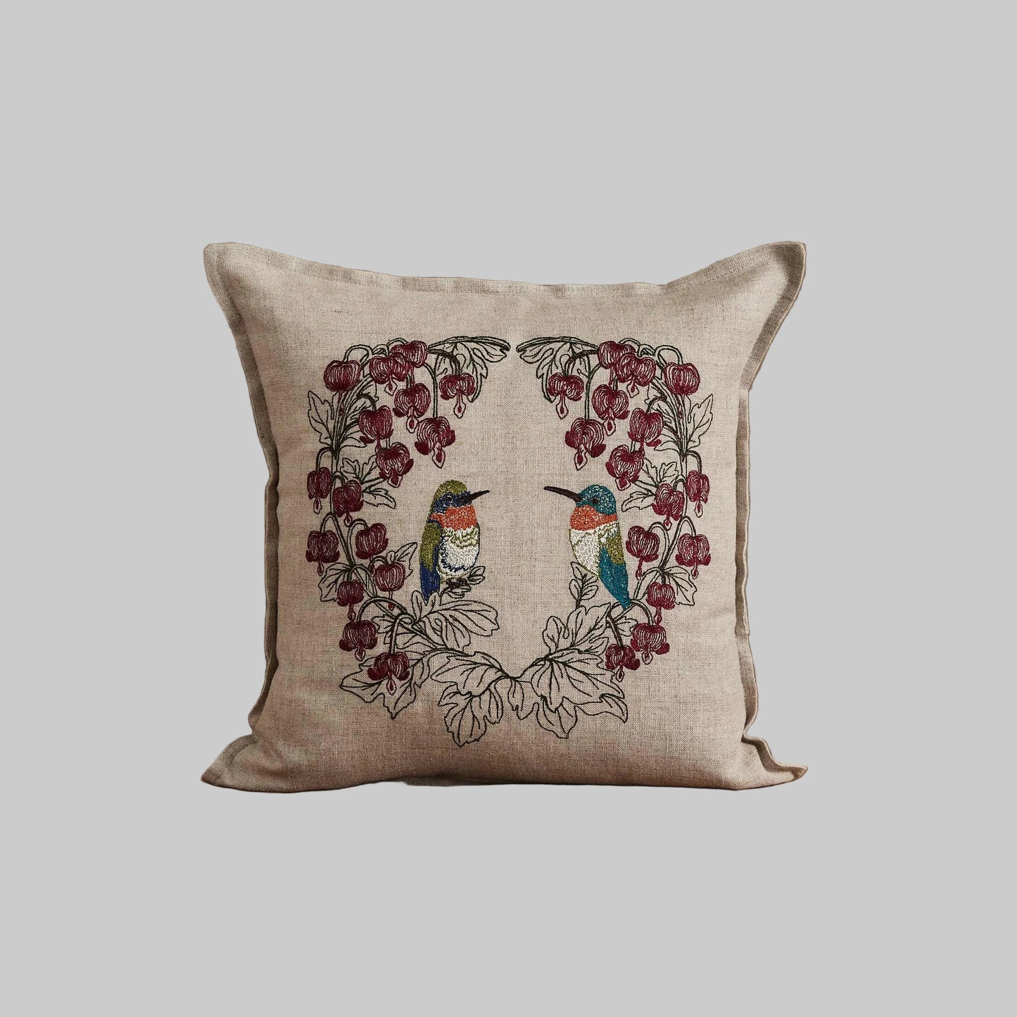 Coral and Tusk’s “Hummingbird Hearts” pillow embroidered with two hummingbirds and bleeding heart flowers, measures 12” x 12”