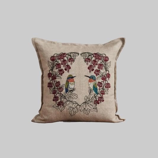 Coral and Tusk’s “Hummingbird Hearts” pillow embroidered with two hummingbirds and bleeding heart flowers, measures 12” x 12”