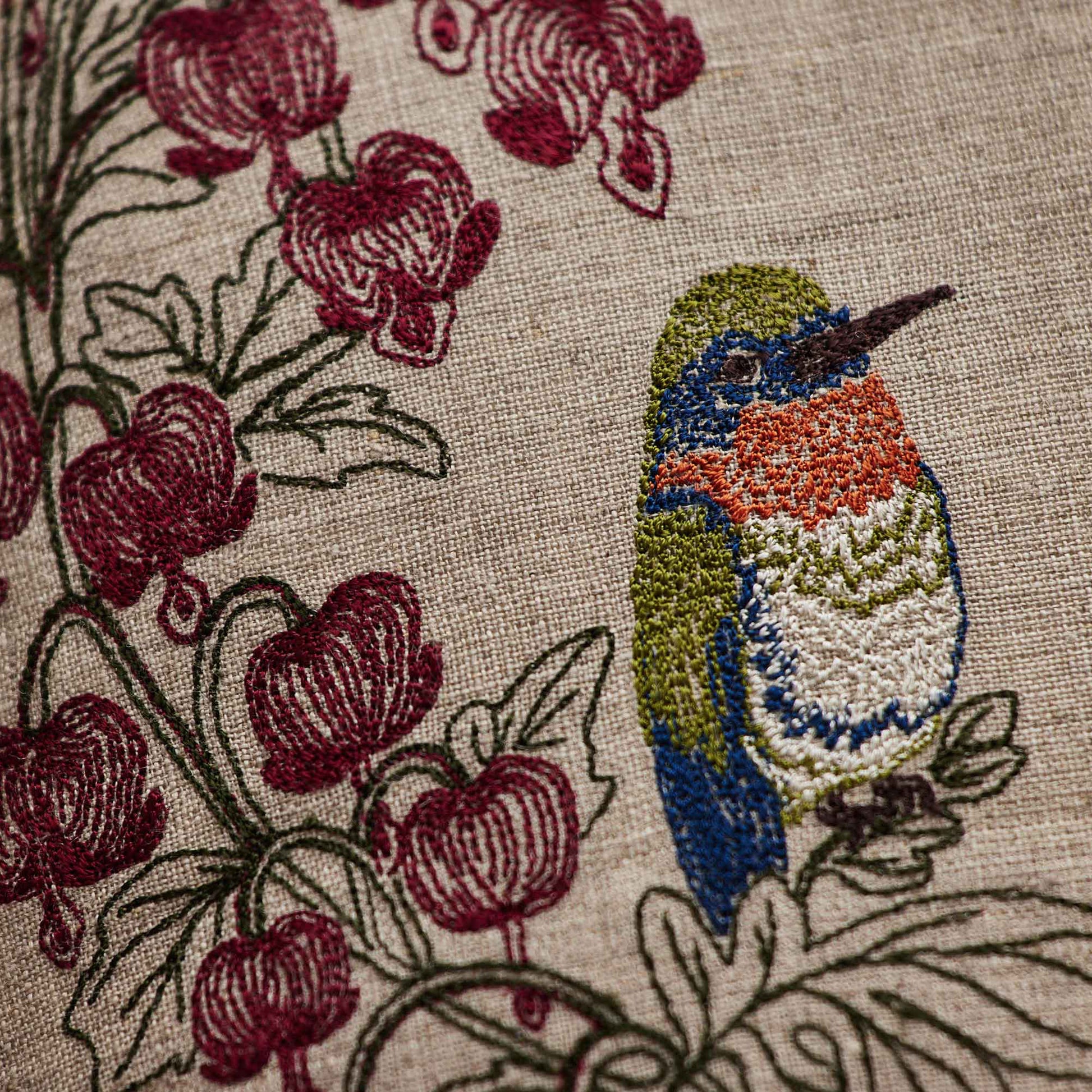 Coral and Tusk’s “Hummingbird Hearts” pillow embroidered with two hummingbirds and bleeding heart flowers, measures 12” x 12” 