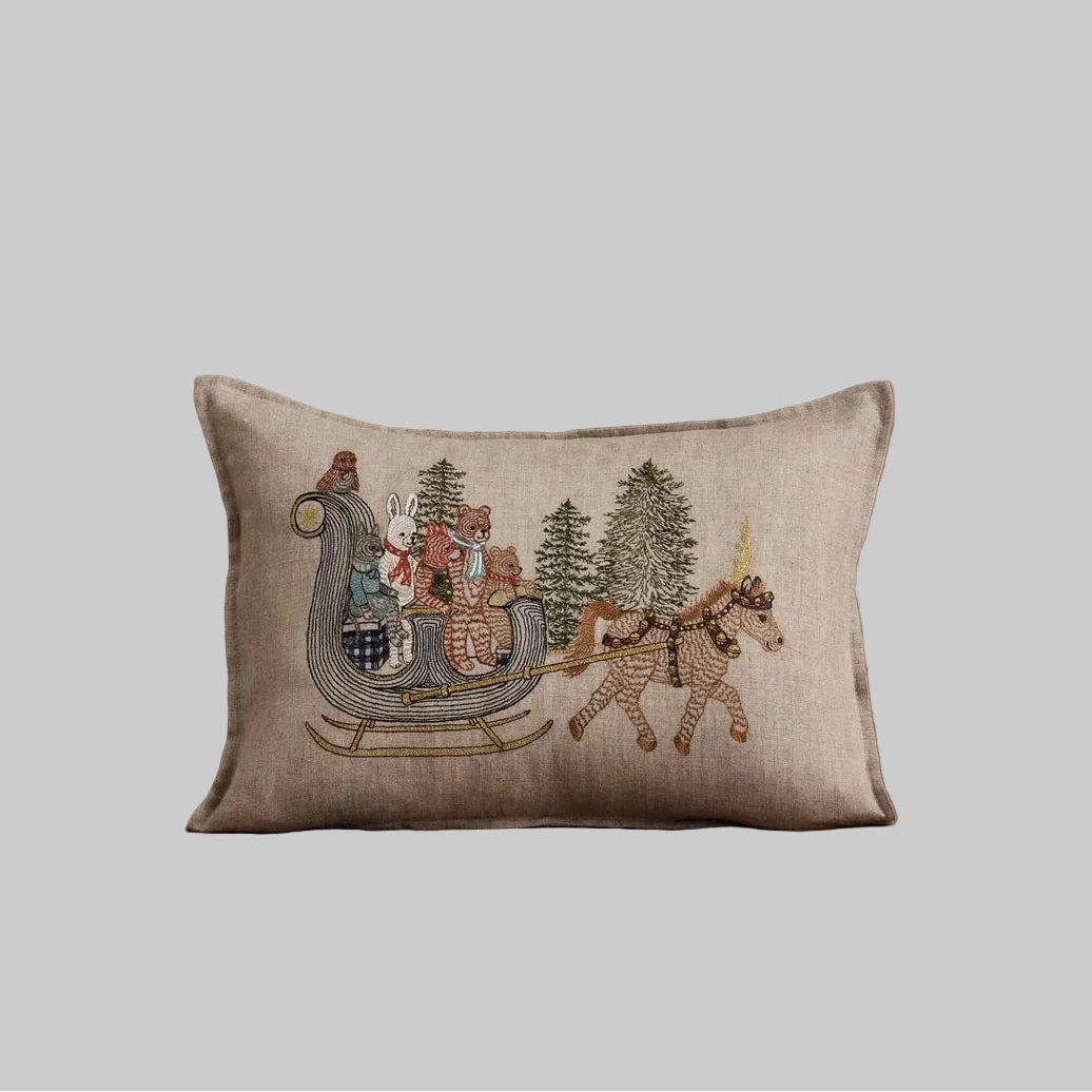 Coral and Tusk's "Jingle Bells" embroidered linen pillow featuring a design of forest friends riding though the woods on a sleigh
