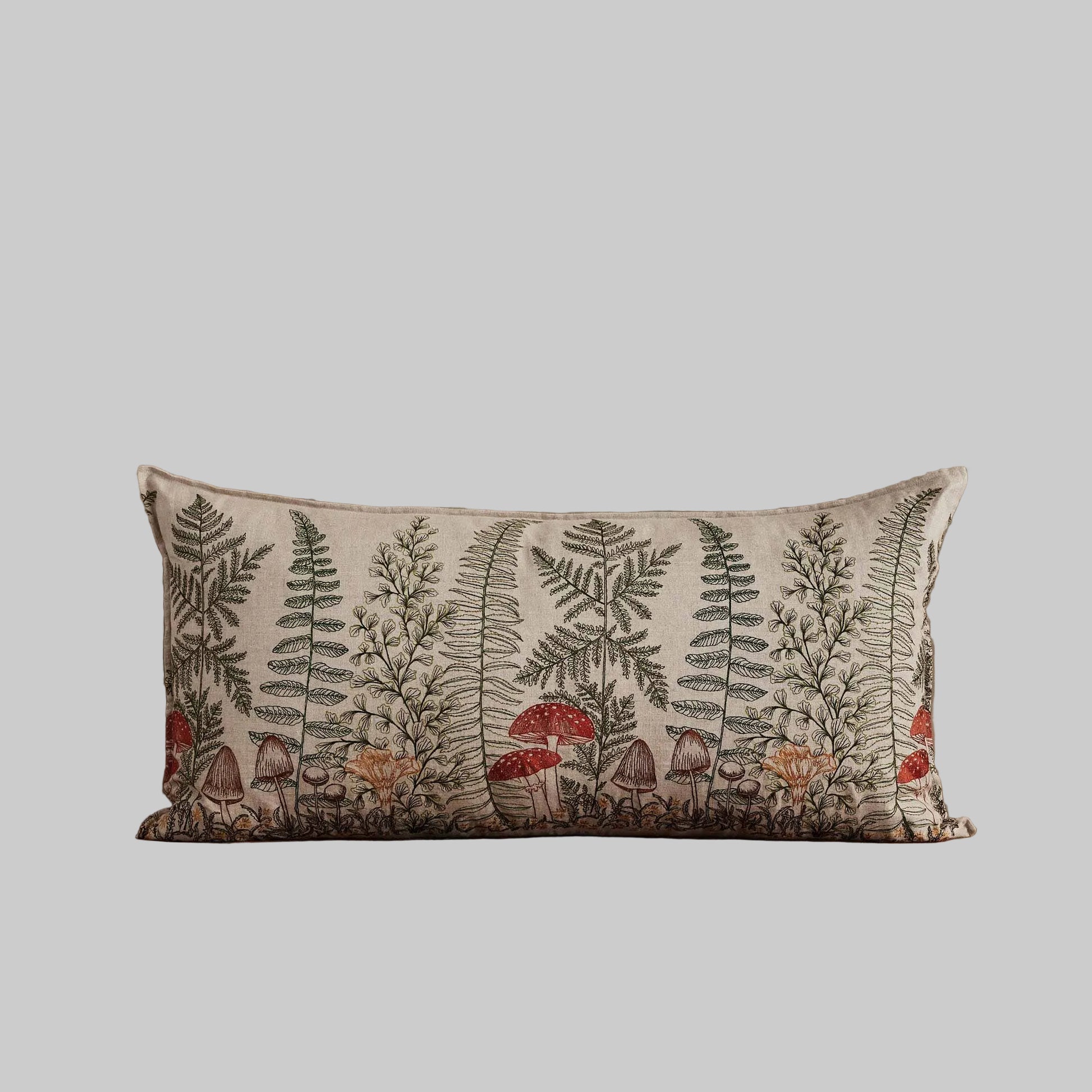 Coral and Tusk’s “Mushrooms and Ferns” embroidered linen lumbar pillow featuring a shade garden of ferns intertwined with a treasure trove of mushrooms, measures 16” x 32”
