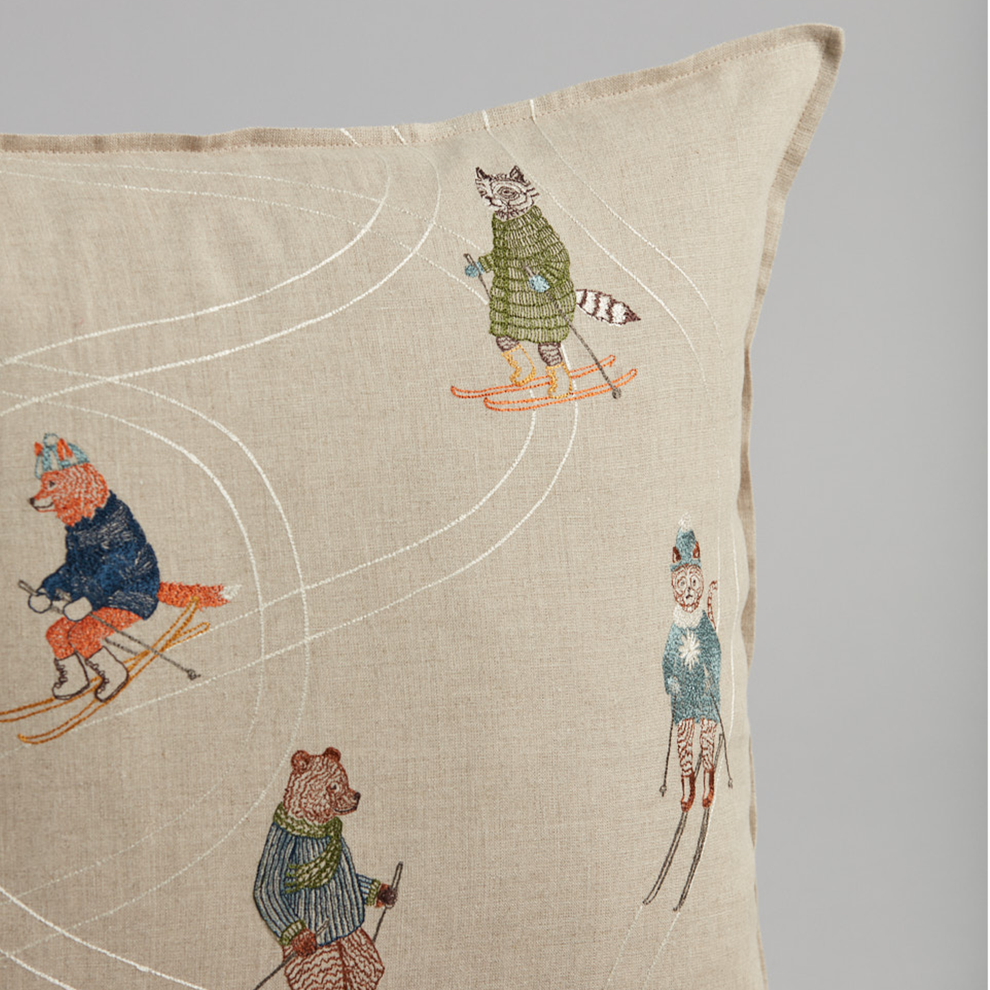 Coral and Tusk's "Downhill Skiers" embroidered linen pillow featuring five fun friends in colorful coats zipping down an alpine slope, measures 20" x 20"