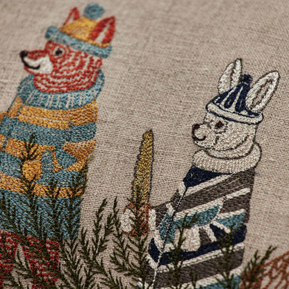 Coral and Tusk’s “Christmas Tree Sled” embroidered linen pillow featuring animal friends venturing out to cut down a pine tree, measures 12” x 16”