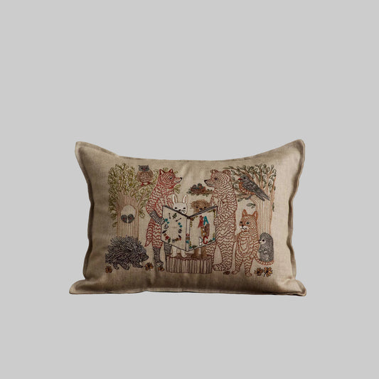 Coral and Tusk’s “Storytime” embroidered linen pillow featuring woodland animal friends gathered around listening to an A-B-C book be read aloud 