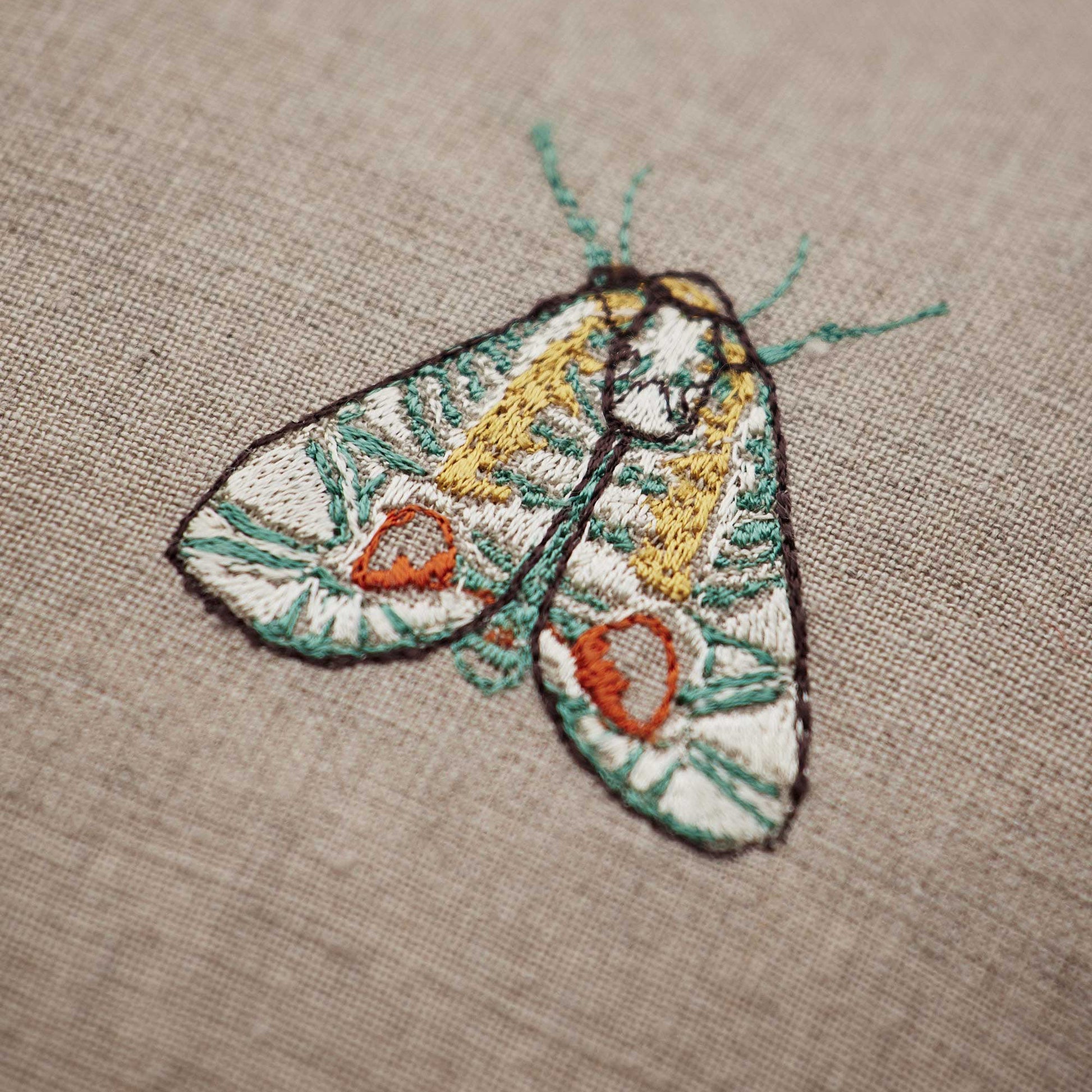 Coral and Tusk’s “Wings Pattern” embroidered linen pillow featuring vibrantly embellished beetles and moths, measures 20” x 20”