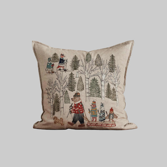 Coral and Tusk’s “Winter Fun” embroidered linen pillow featuring woodland animals in sweaters ushering in the winter solstice by sledding and skiing, measures 20” x 20”