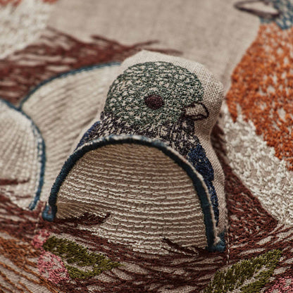 Coral and Tusk’s “Bluebird Nest” embroidered linen pocket pillow featuring a family of bluebirds in a cherry blossom tree, measures 12” x 16”