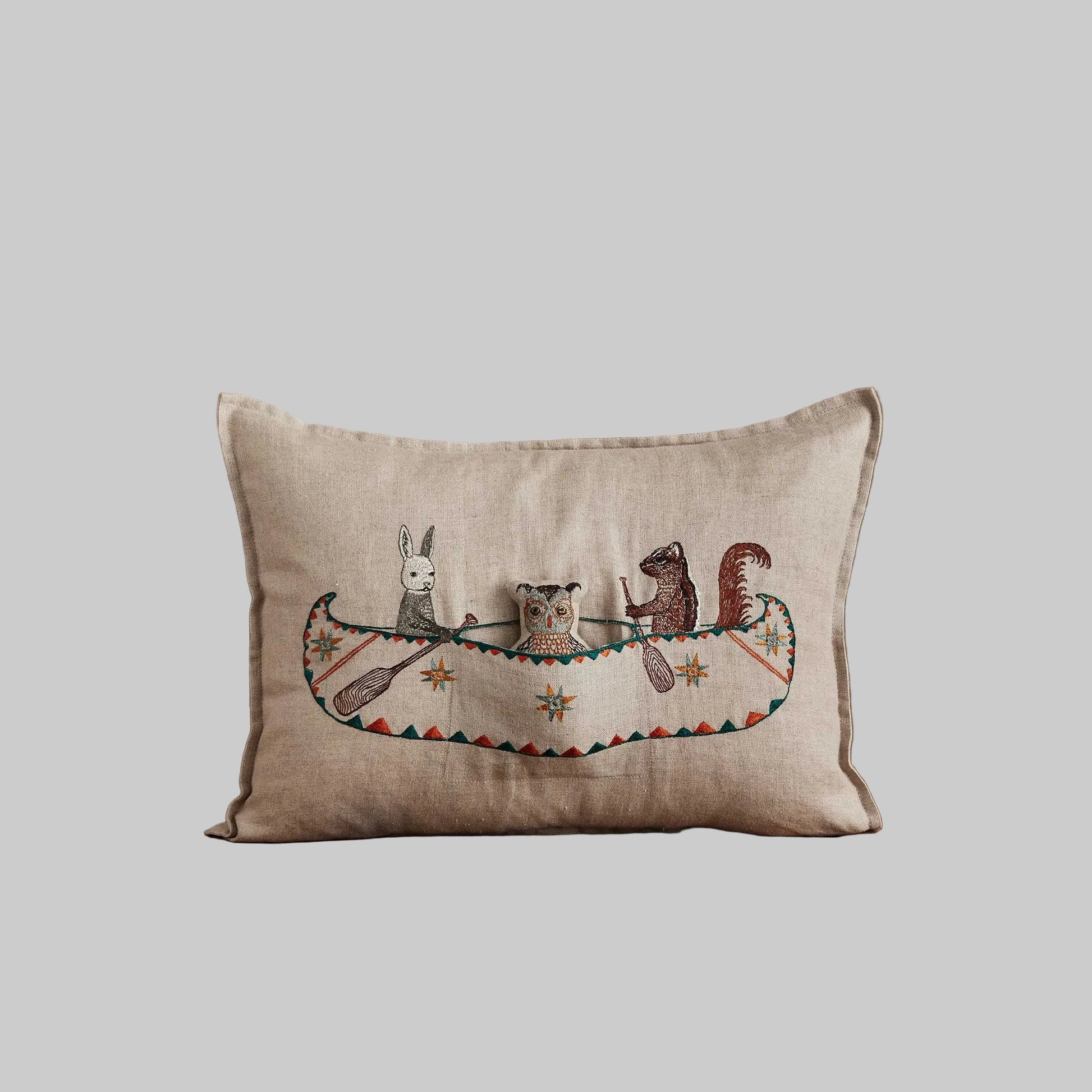 Coral and Tusk’s “Friend’s Canoe” embroidered linen pocket pillow featuring three woodland friends paddling in a canoe, measures 12” x 16”
