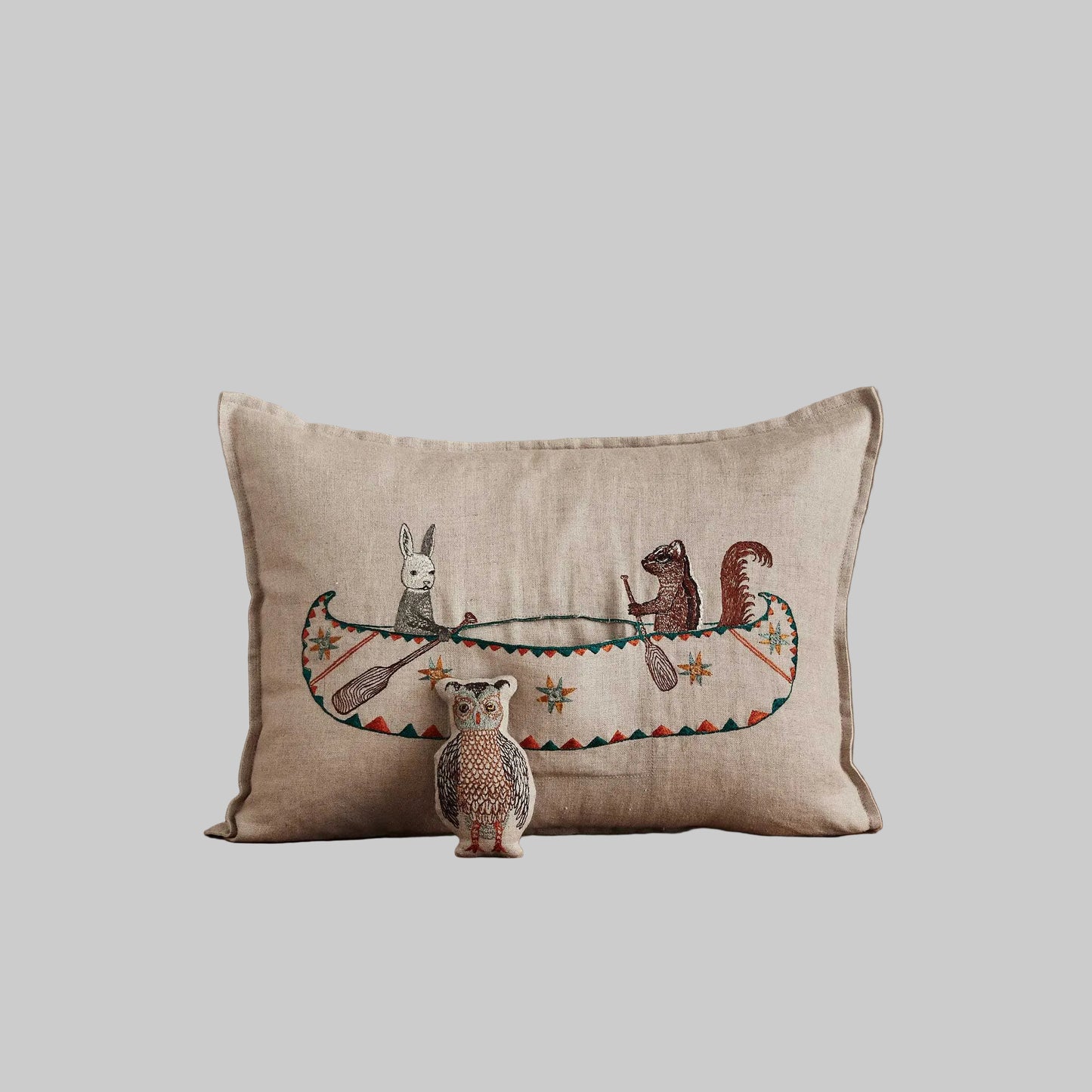 Coral and Tusk’s “Friend’s Canoe” embroidered linen pocket pillow featuring three woodland friends paddling in a canoe, measures 12” x 16”