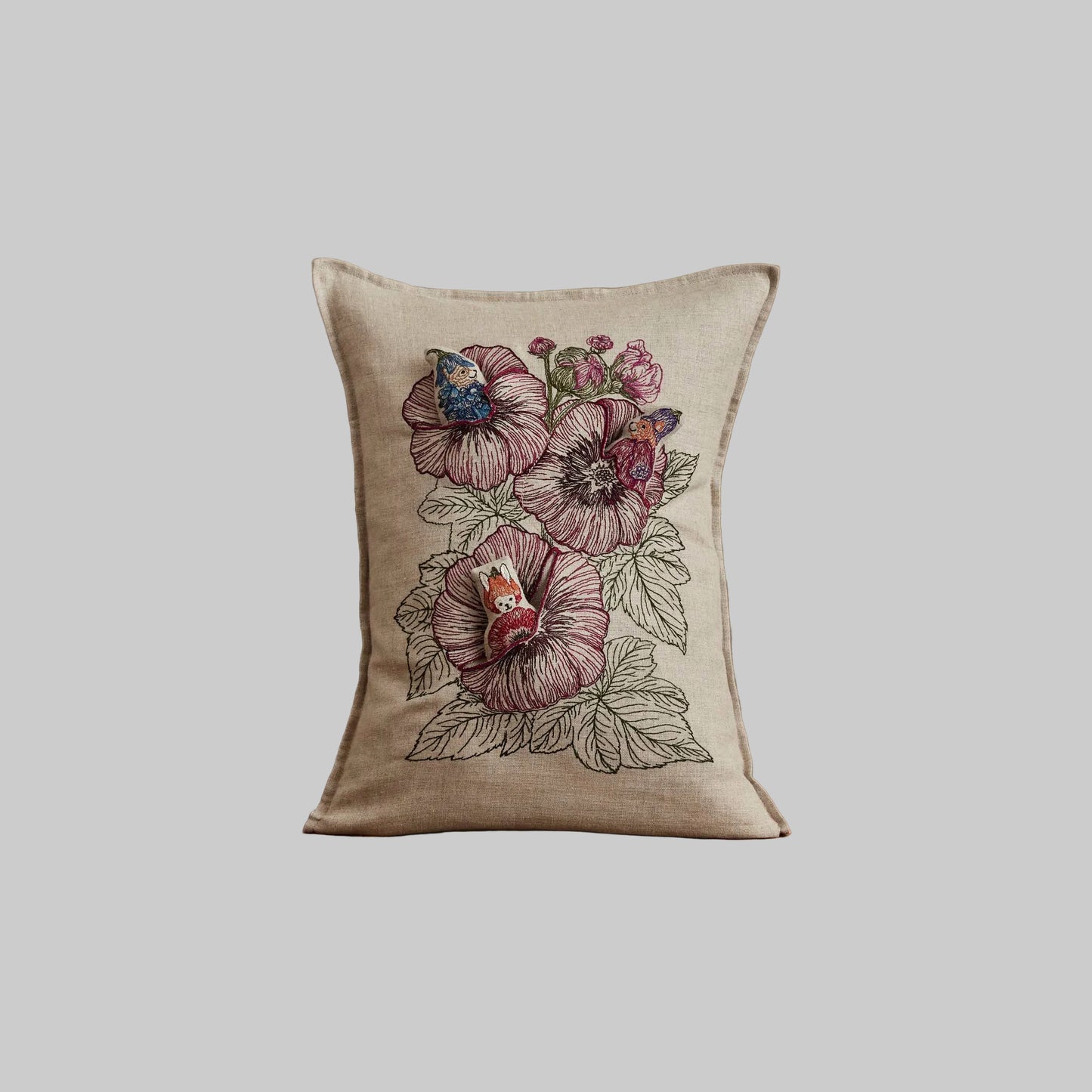 Coral and Tusk’s “Fairy Bloom” embroidered linen pocket pillow featuring three animal fairies hiding among some spring flowers, measures 12” x 16”