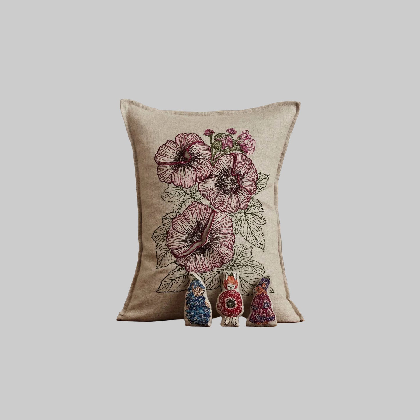 Coral and Tusk’s “Fairy Bloom” embroidered linen pocket pillow featuring three animal fairies hiding among some spring flowers, measures 12” x 16”