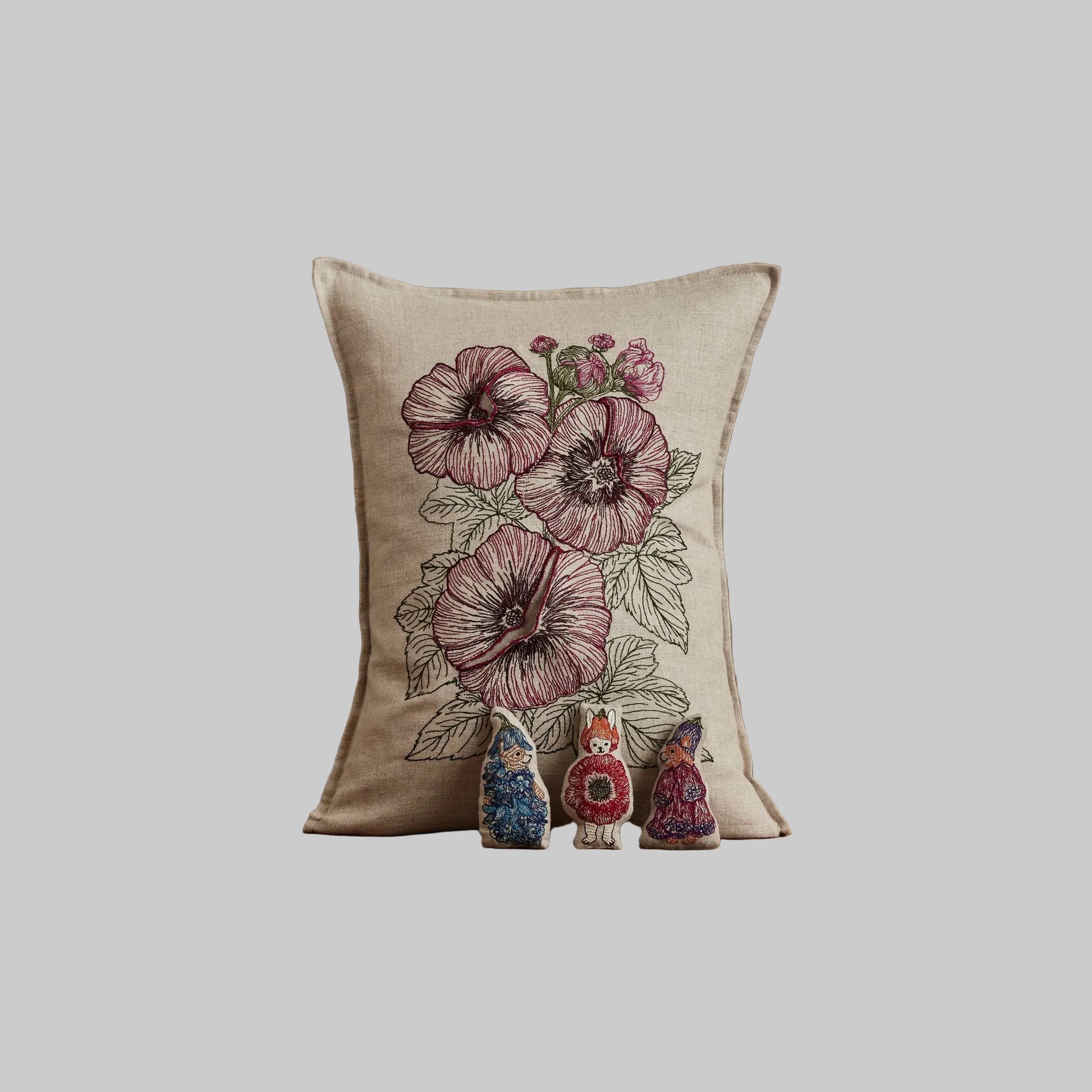 Coral and Tusk’s “Fairy Bloom” embroidered linen pocket pillow featuring three animal fairies hiding among some spring flowers, measures 12” x 16”