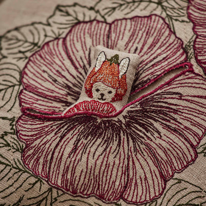 Coral and Tusk’s “Fairy Bloom” embroidered linen pocket pillow featuring three animal fairies hiding among some spring flowers, measures 12” x 16”
