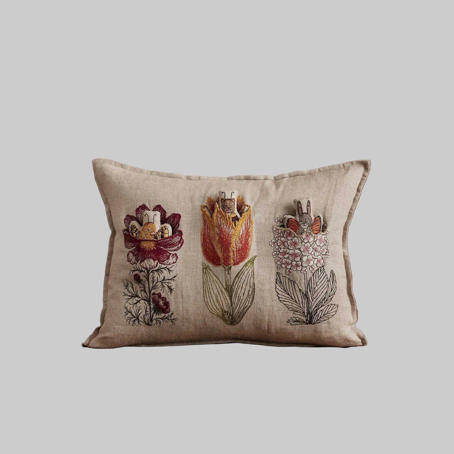 Coral and Tusk’s “Flower Friends” embroidered linen pocket pillow featuring the first flowers of spring with some animal friends hidden in their petals, measures 12” x 16”