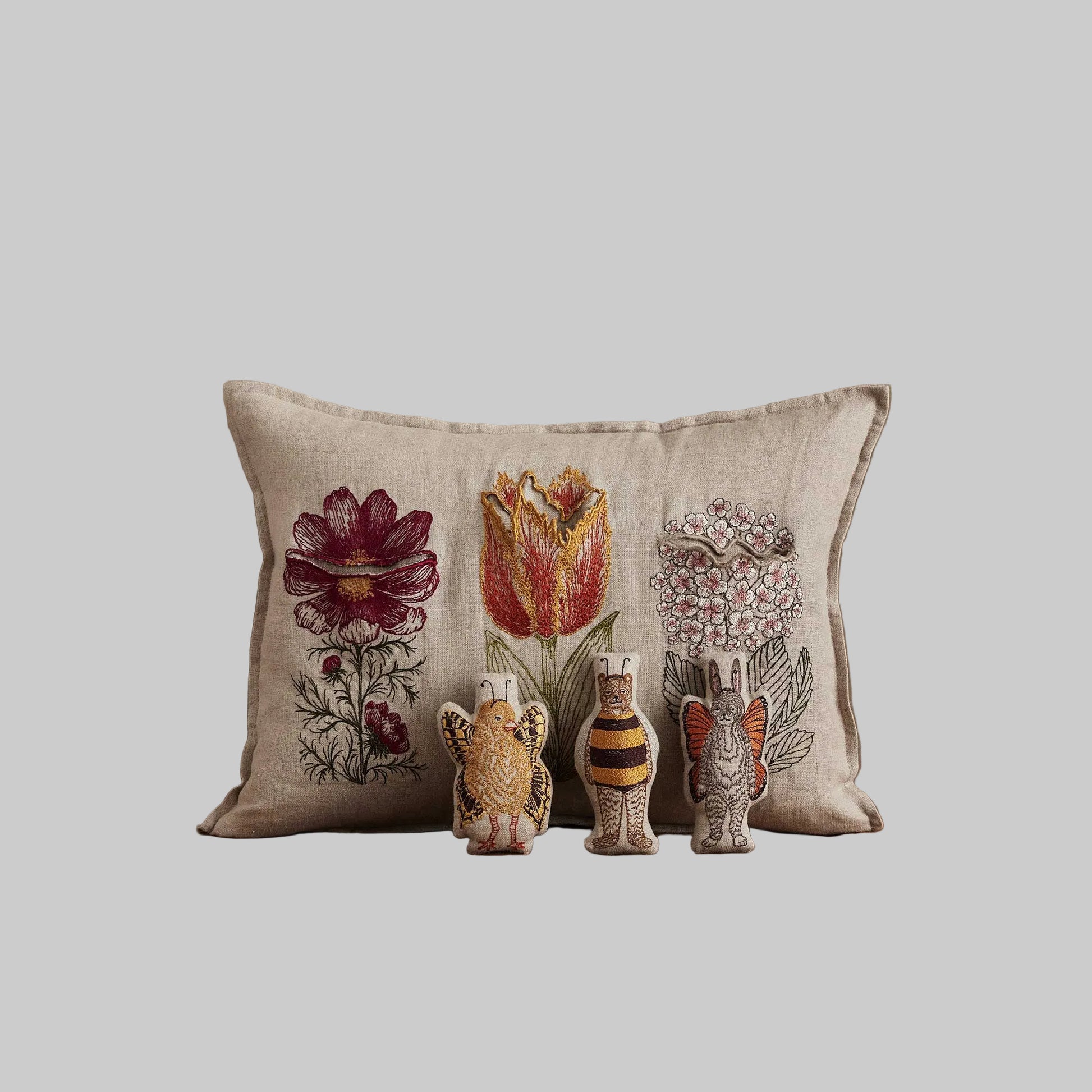 Coral and Tusk’s “Flower Friends” embroidered linen pocket pillow featuring the first flowers of spring with some animal friends hidden in their petals, measures 12” x 16”