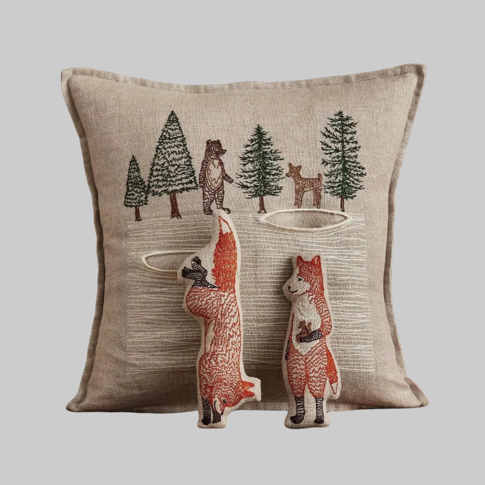 Coral and Tusk’s “Winter Foxes” embroidered linen pocket pillow featuring two foxes in the middle of a hunt, measures 12” x 12”