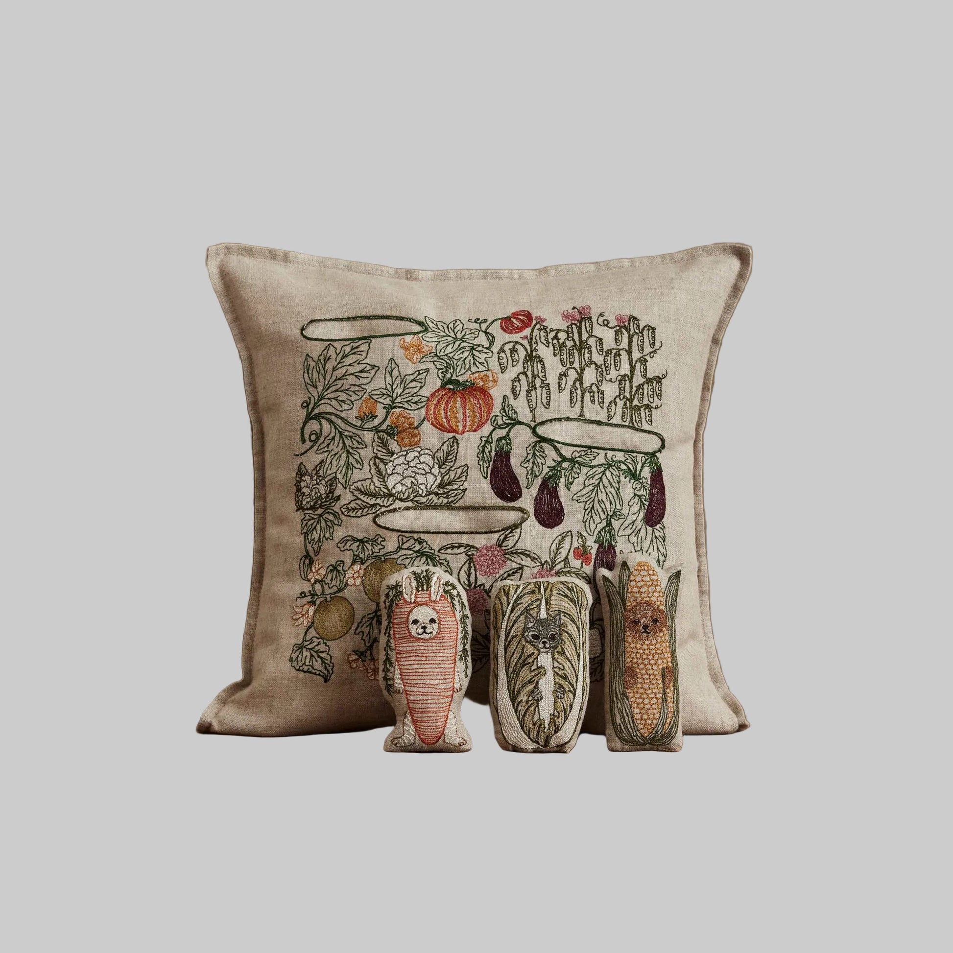 Coral and Tusk’s “Garden Patch” embroidered linen pocket pillow featuring a vegetable garden scene with three removable pals