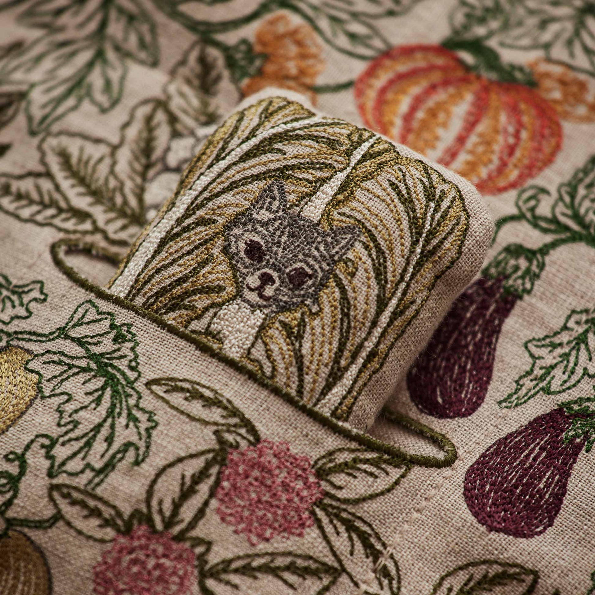 Coral and Tusk’s “Garden Patch” embroidered linen pocket pillow featuring a vegetable garden scene with three removable pals