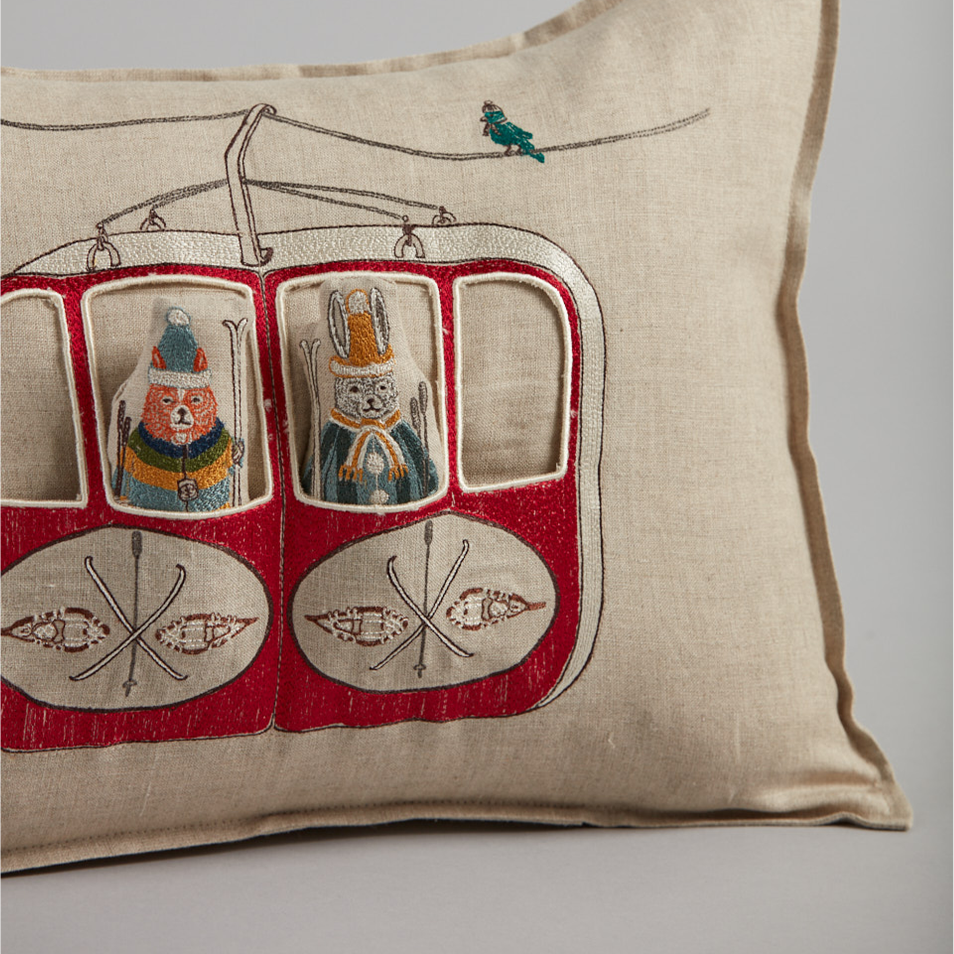 Coral and Tusk's "Gondola Ski Lift" embroidered linen pocket pillow featuring fox and bunny in their vintage ski gear riding the gondola, measures 12" x 16"