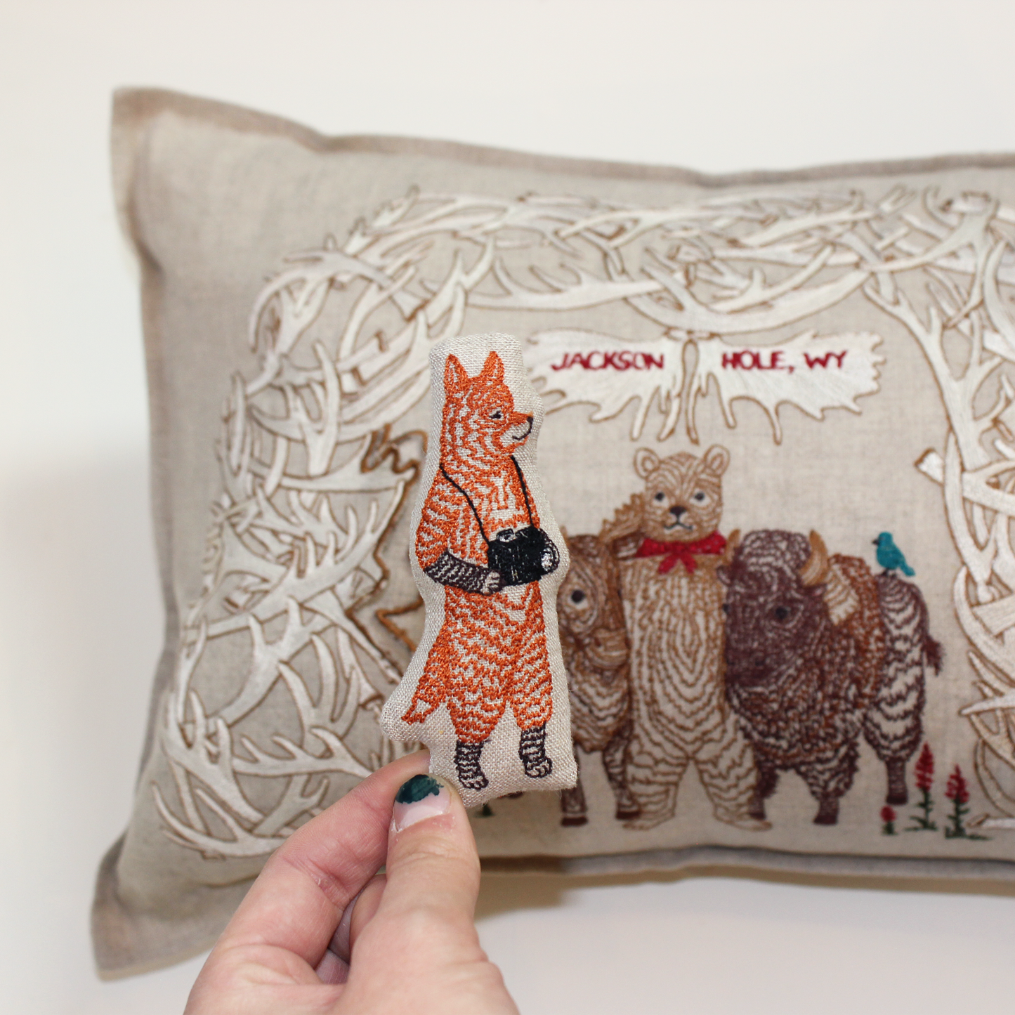 A Workshop x Coral and Tusk collaboration, this pillow features animal friends gathering for a photo under Jackson's iconic Antler Arch, measures 12" x 16"