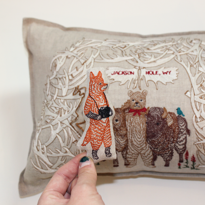 A Workshop x Coral and Tusk collaboration, this pillow features animal friends gathering for a photo under Jackson's iconic Antler Arch, measures 12" x 16"
