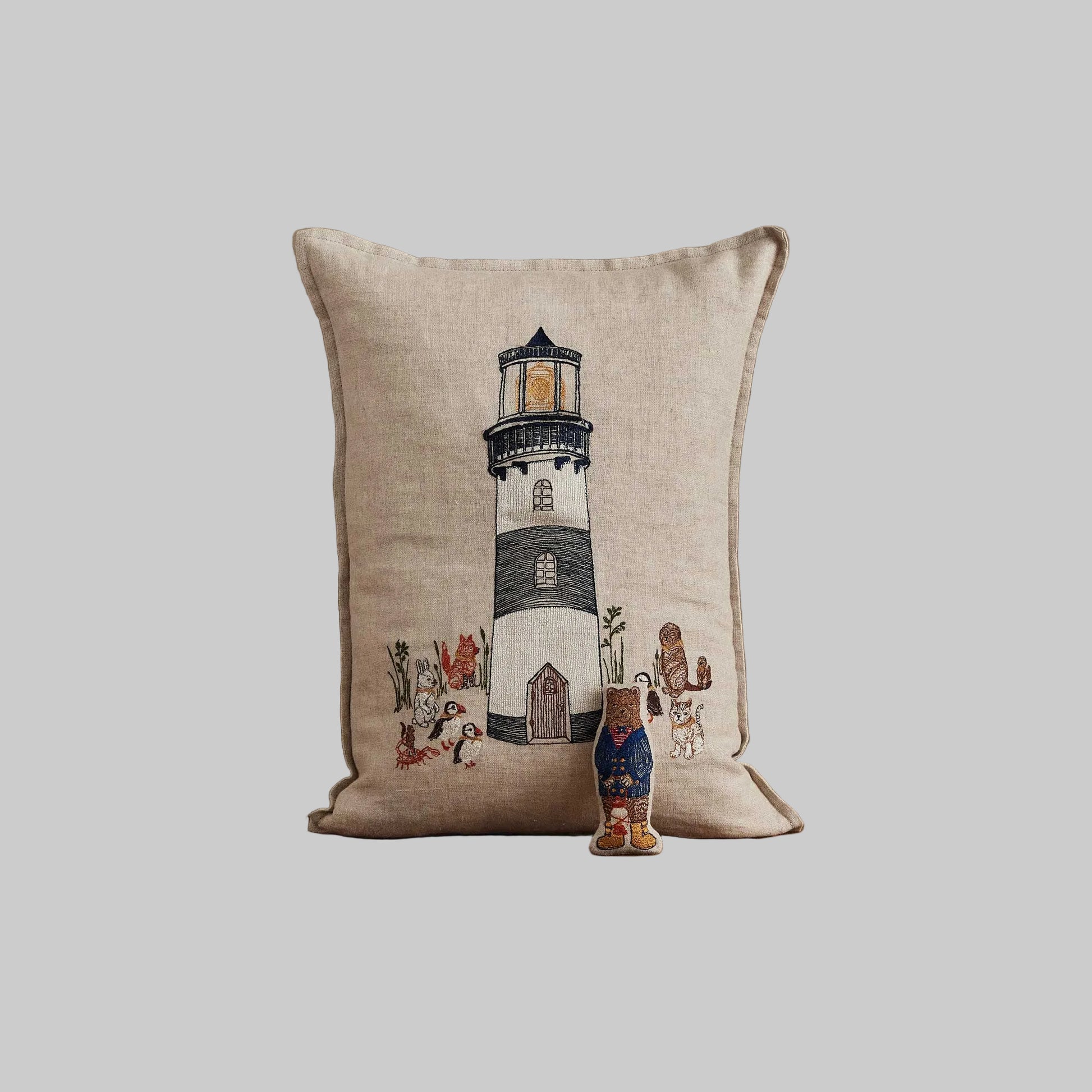 Coral and Tusk’s “Lighthouse Friends embroidered linen pocket pillow featuring a lighthouse keeper bear lighting the way for his nautical friends, measures 12” x 16”