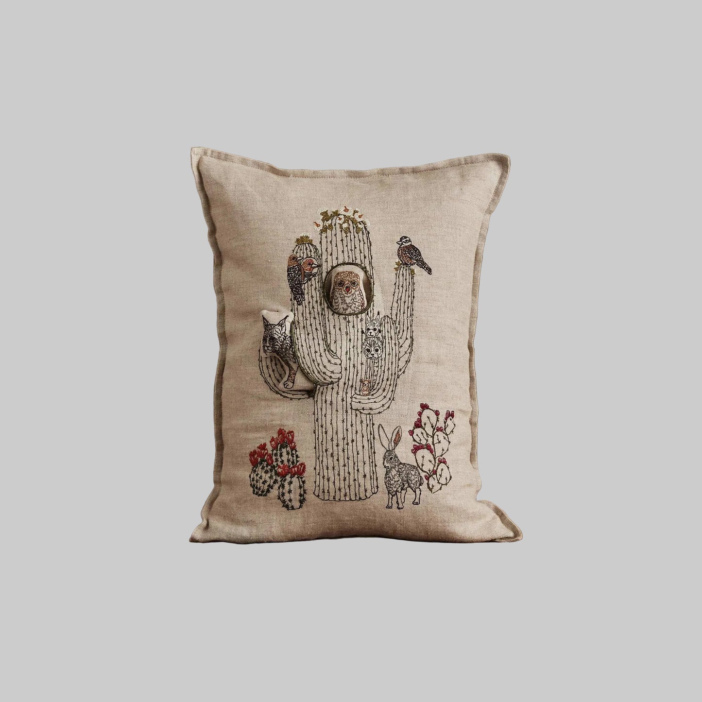 Coral and Tusk’s “Saguaro House” embroidered linen pocket pillow featuring desert animals sheltering in a cactus, measures 12” x 16”