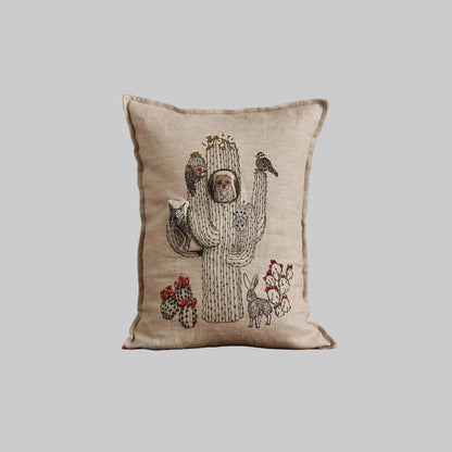 Coral and Tusk’s “Saguaro House” embroidered linen pocket pillow featuring desert animals sheltering in a cactus, measures 12” x 16”