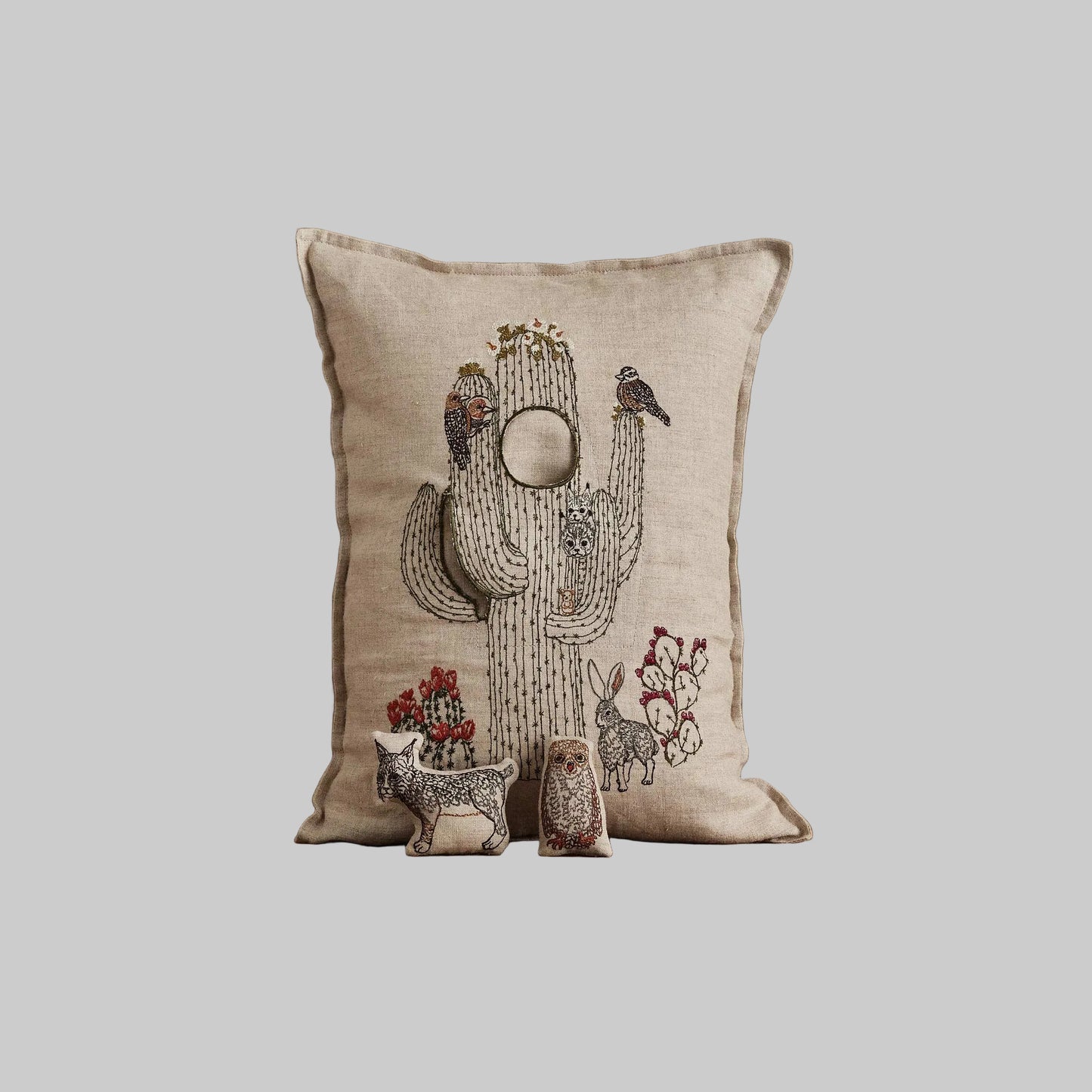Coral and Tusk’s “Saguaro House” embroidered linen pocket pillow featuring desert animals sheltering in a cactus, measures 12” x 16”