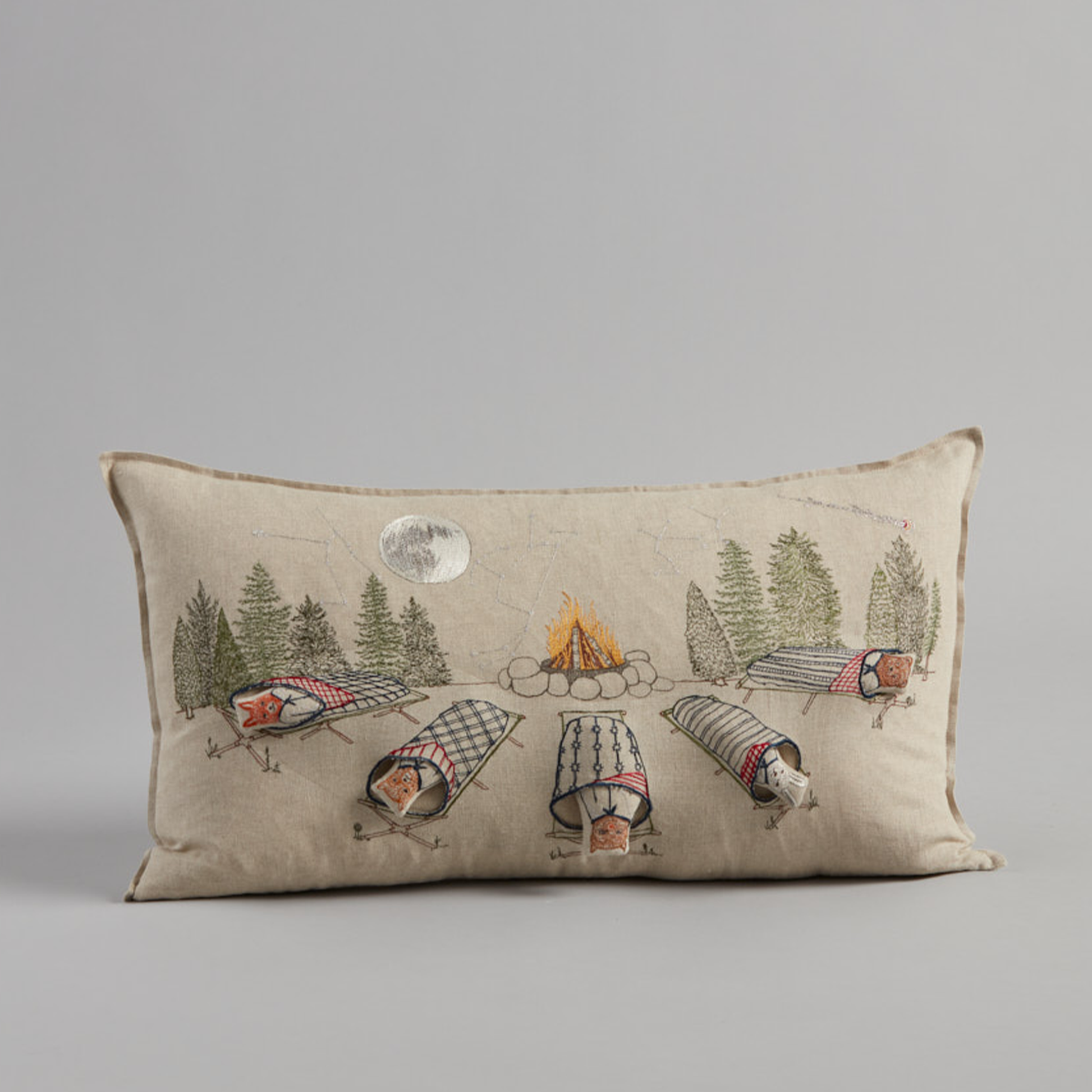 Coral and Tusk's "Stargazers" embroidered linen pocket pillow featuring five removable pals resting in quilted sleeping bags staring up at the stars, measures 14" x 26"