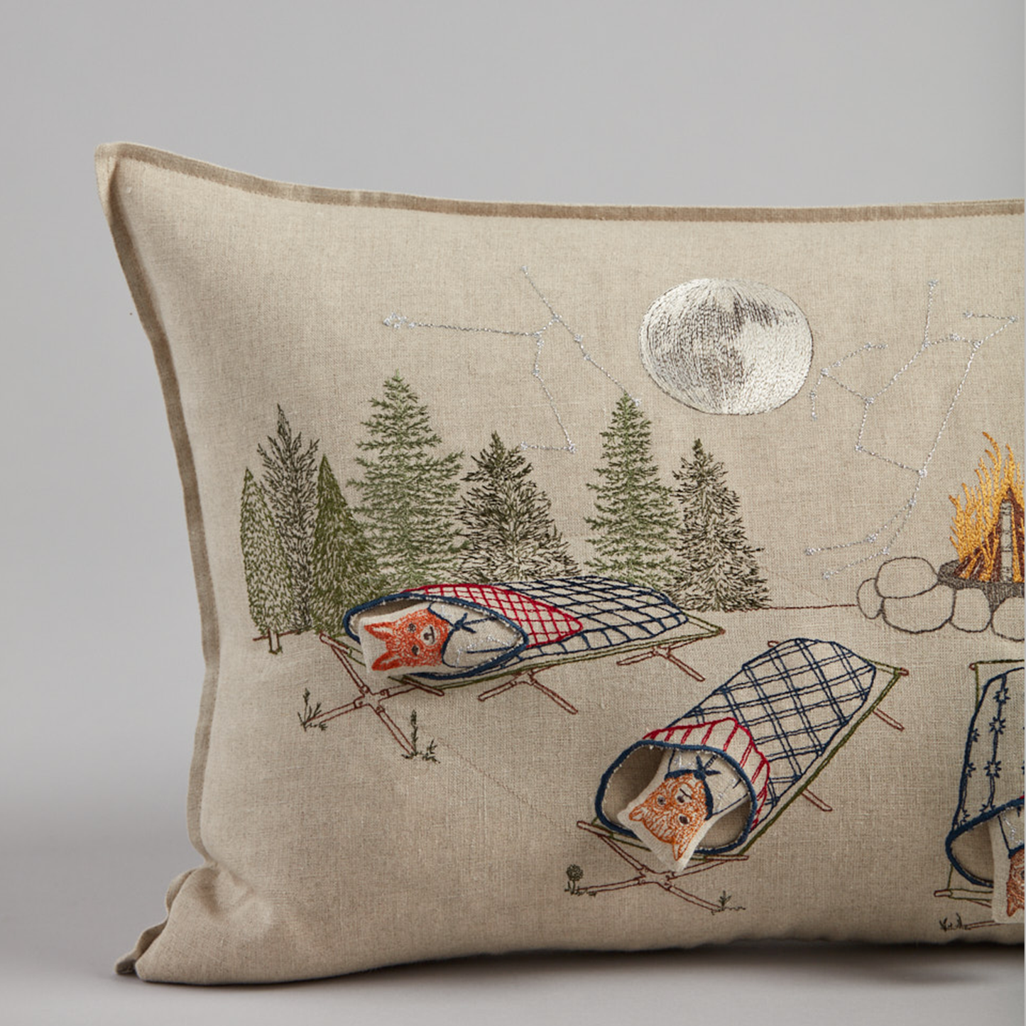 Coral and Tusk's "Stargazers" embroidered linen pocket pillow featuring five removable pals resting in quilted sleeping bags staring up at the stars, measures 14" x 26"
