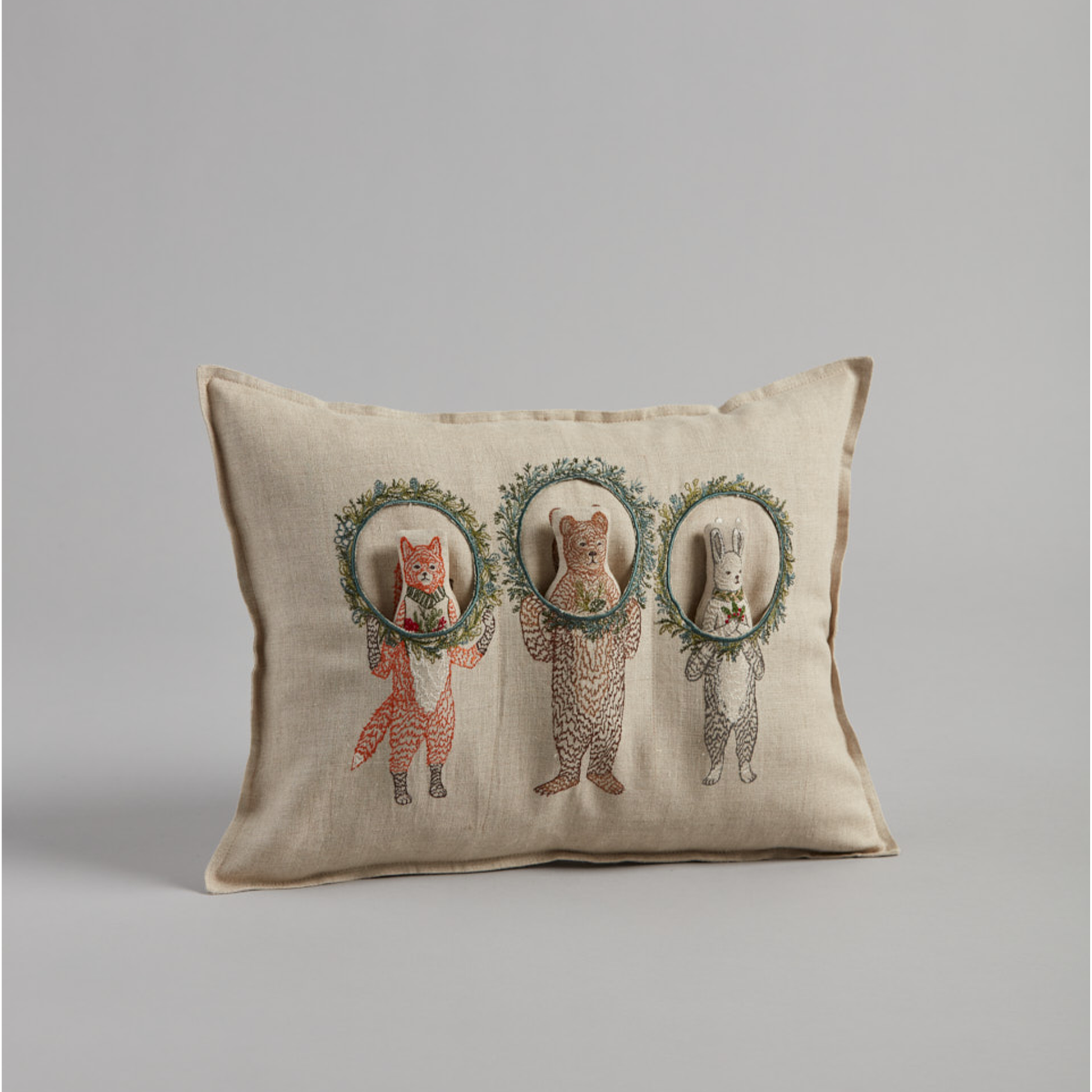 Coral and Tusk's "Christmas Wreath Trio" embroidered linen pocket pillow featuring  three woodland friends celebrating the holiday season with Christmas wreaths, measures 12" x 16"