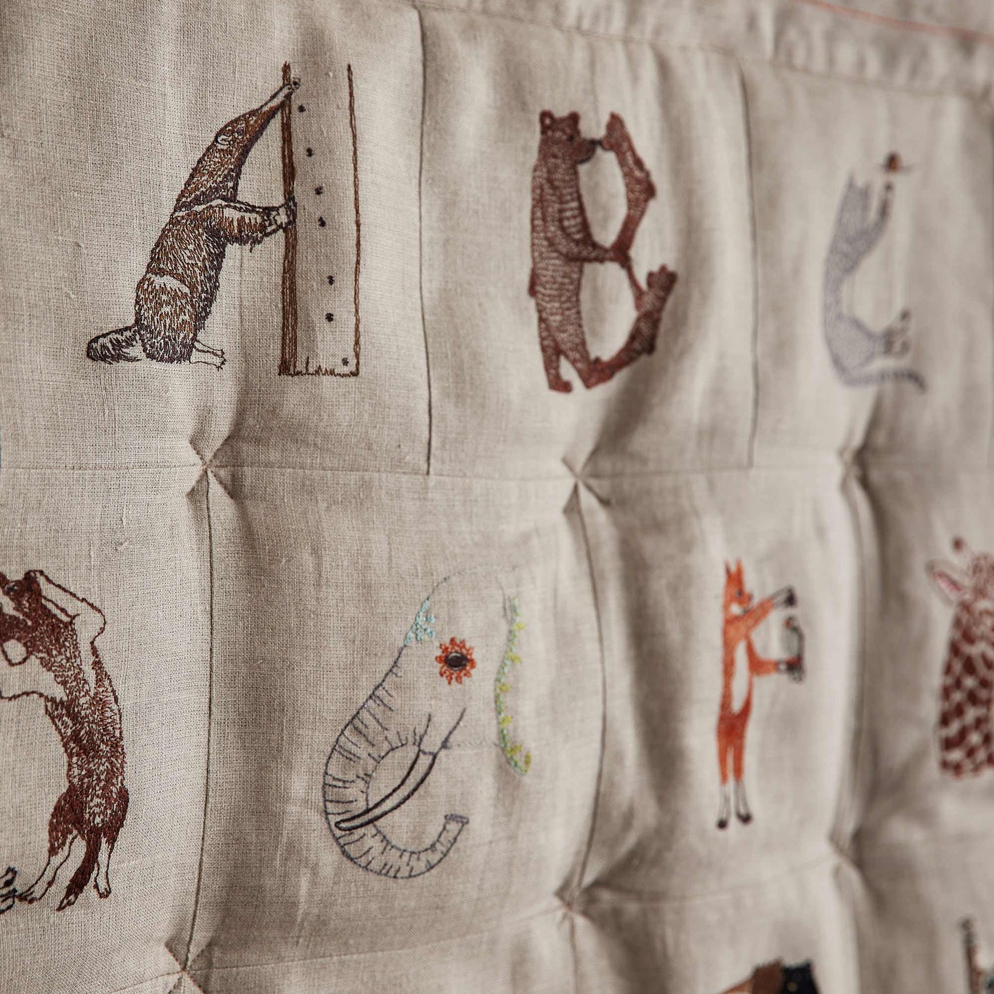 Coral and Tusk's embroidered linen quilt for children or a nursery. Feature alphabet designs with animals playfully representing each letter.