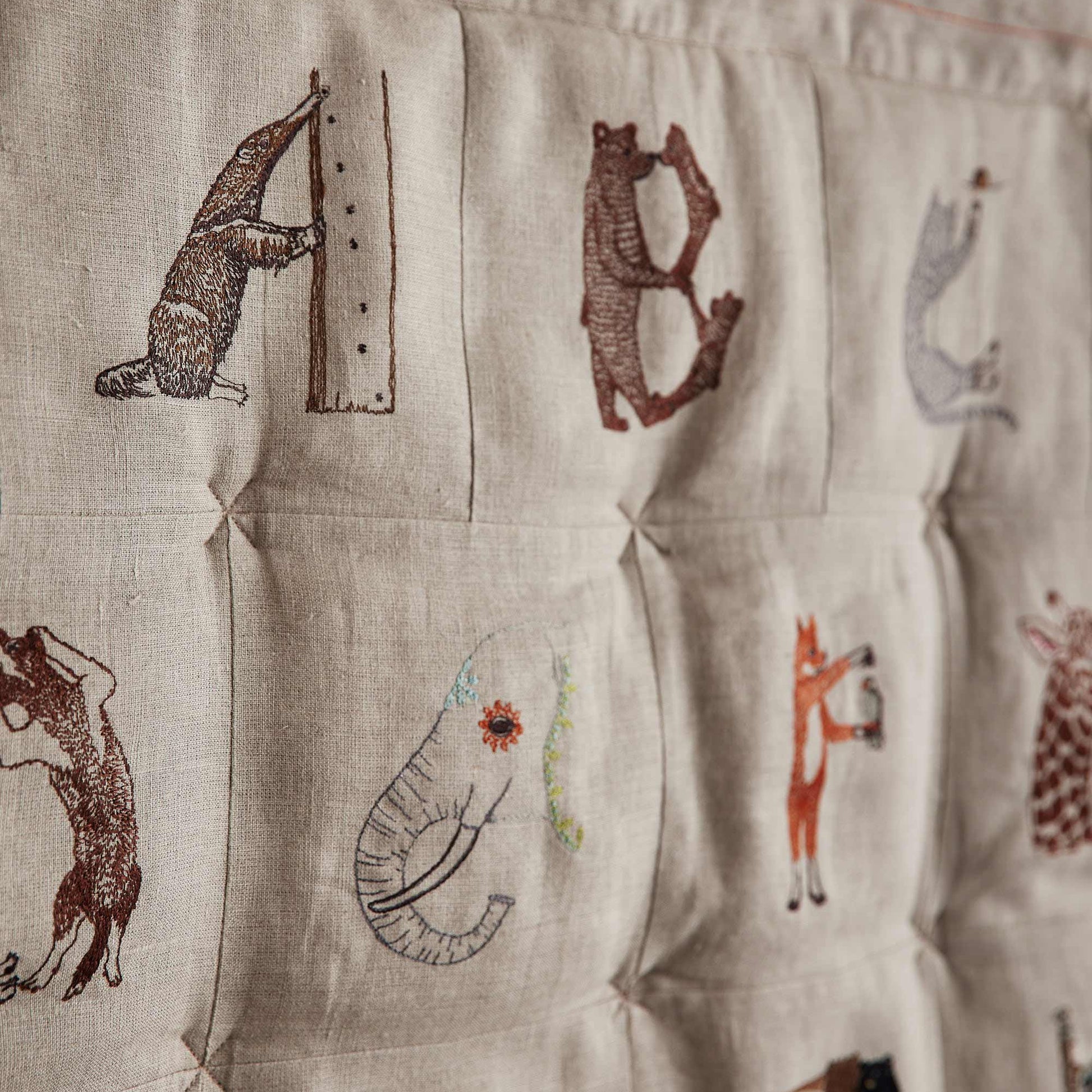 Coral and Tusk's embroidered linen quilt for children or a nursery. Feature alphabet designs with animals playfully representing each letter.
