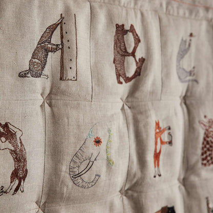 Coral and Tusk's embroidered linen quilt for children or a nursery. Feature alphabet designs with animals playfully representing each letter.