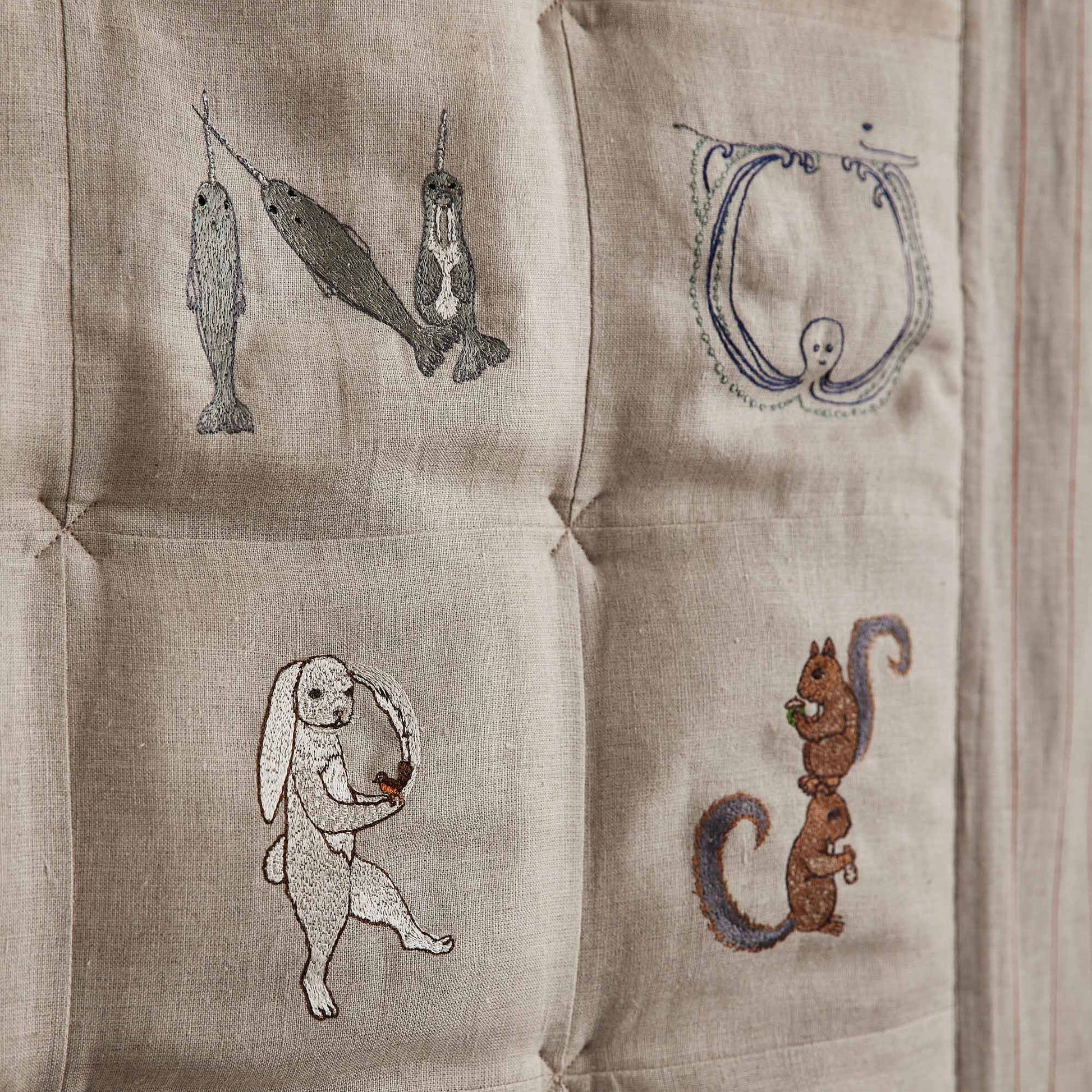 Coral and Tusk's embroidered linen quilt for children or a nursery. Feature alphabet designs with animals playfully representing each letter.