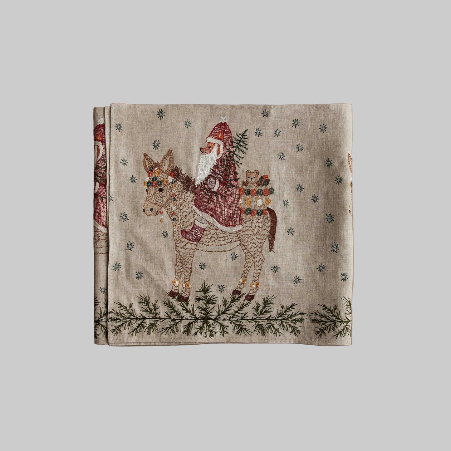 Coral and Tusk’s “Christmas Donkey” embroidered linen table runner featuring a fox Santa carrying presents in on a festive donkey
