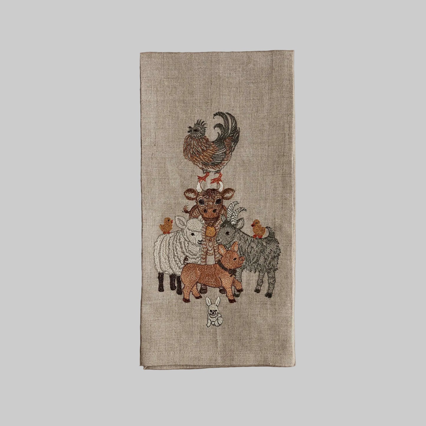 Coral and Tusk’s “Barnyard Friends” embroidered linen tea towel featuring a pyramid stack of farm animals