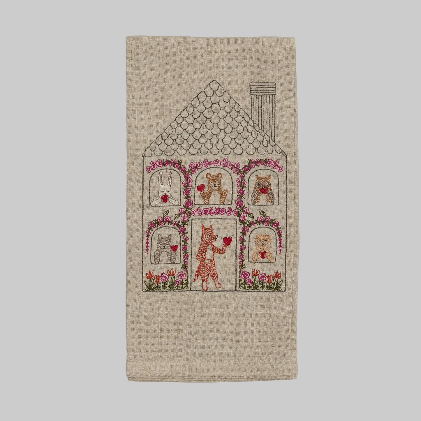 Coral and Tusk’s “Home is Where the Heart Is” embroidered linen tea towel featuring a house with animal friends sharing valentines 