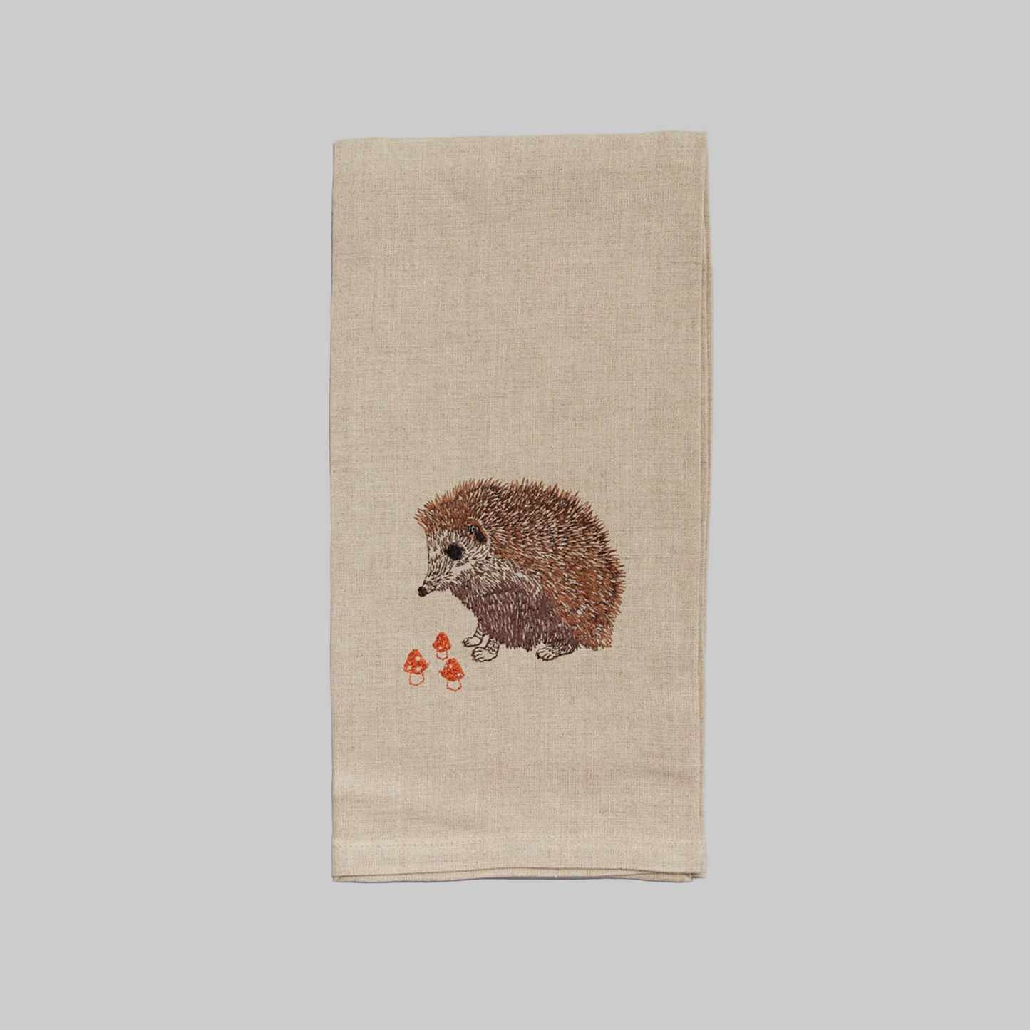 Coral and Tusk’s “Hedgehog with Mushrooms” embroidered linen tea towel featuring a hedgehog with three tiny mushrooms