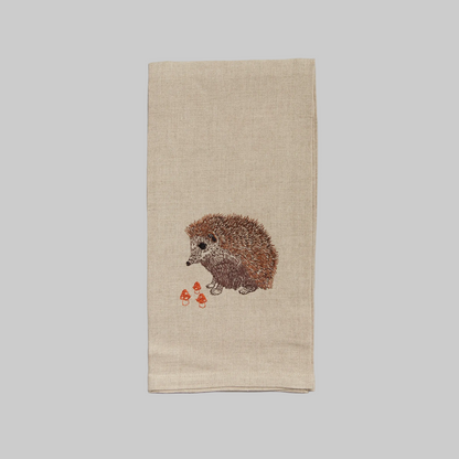 Coral and Tusk’s “Hedgehog with Mushrooms” embroidered linen tea towel featuring a hedgehog with three tiny mushrooms