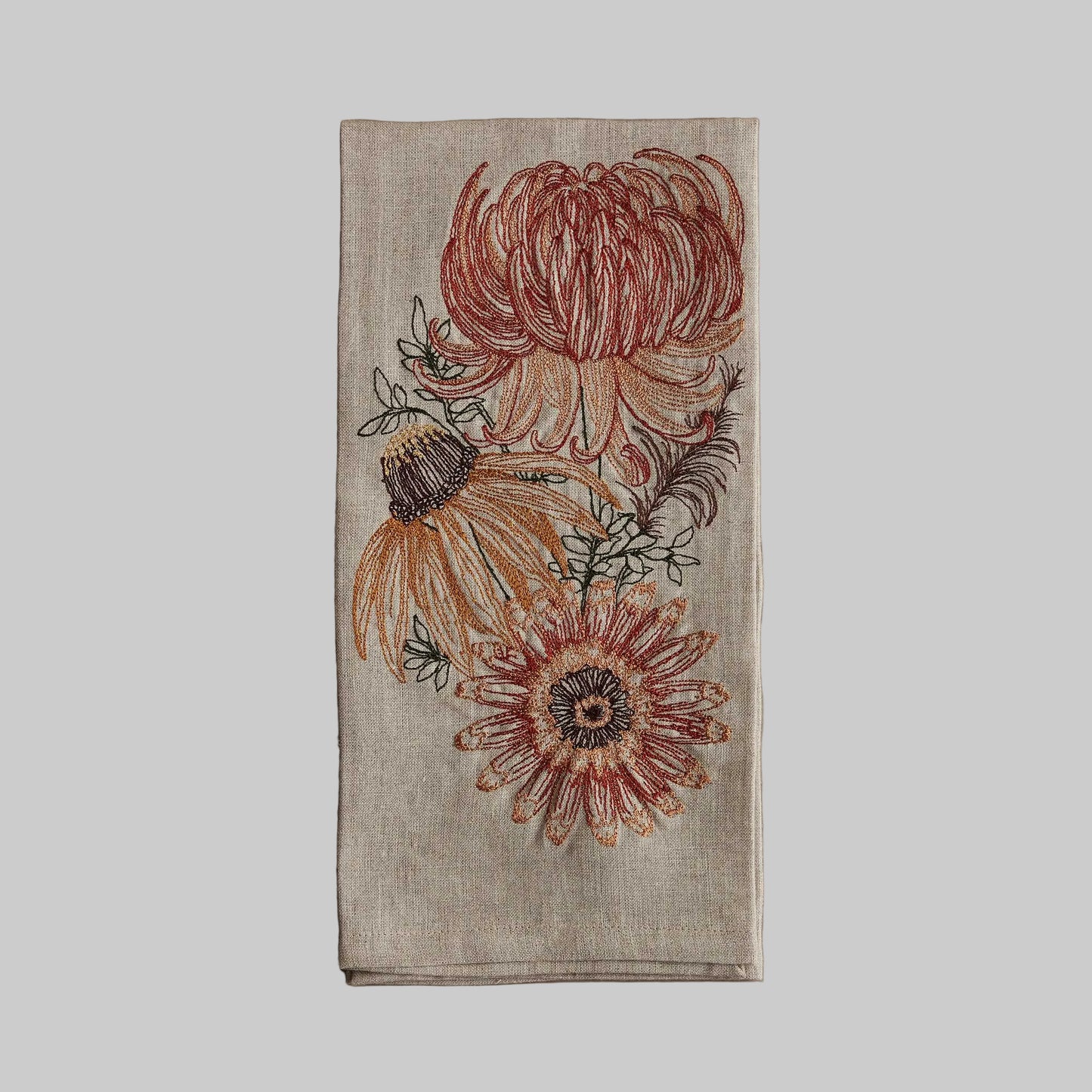 Coral and Tusk’s “Autumn Mums” embroidered linen tea towel featuring flower blooms in earthy tones