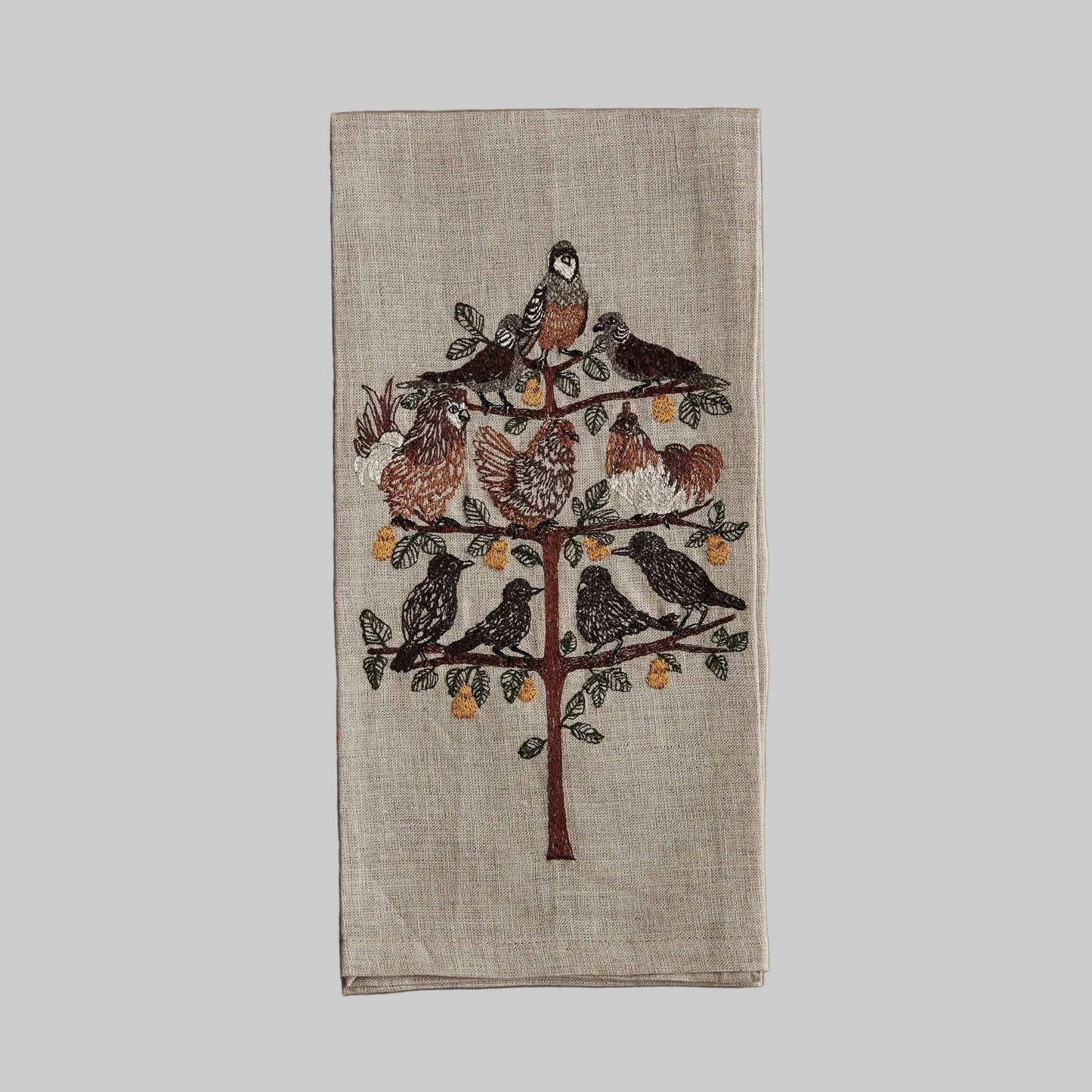 Coral and Tusk’s “Partridge in a Pear Tree” embroidered linen tea towel featuring a variety of birds sitting on the branches of a pear tree