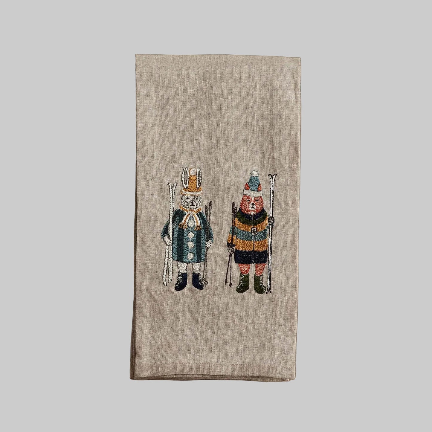 Coral and Tusk's "Ski Buddies" embroidered linen tea towel featuring a fox and rabbit in winter clothes holding skis