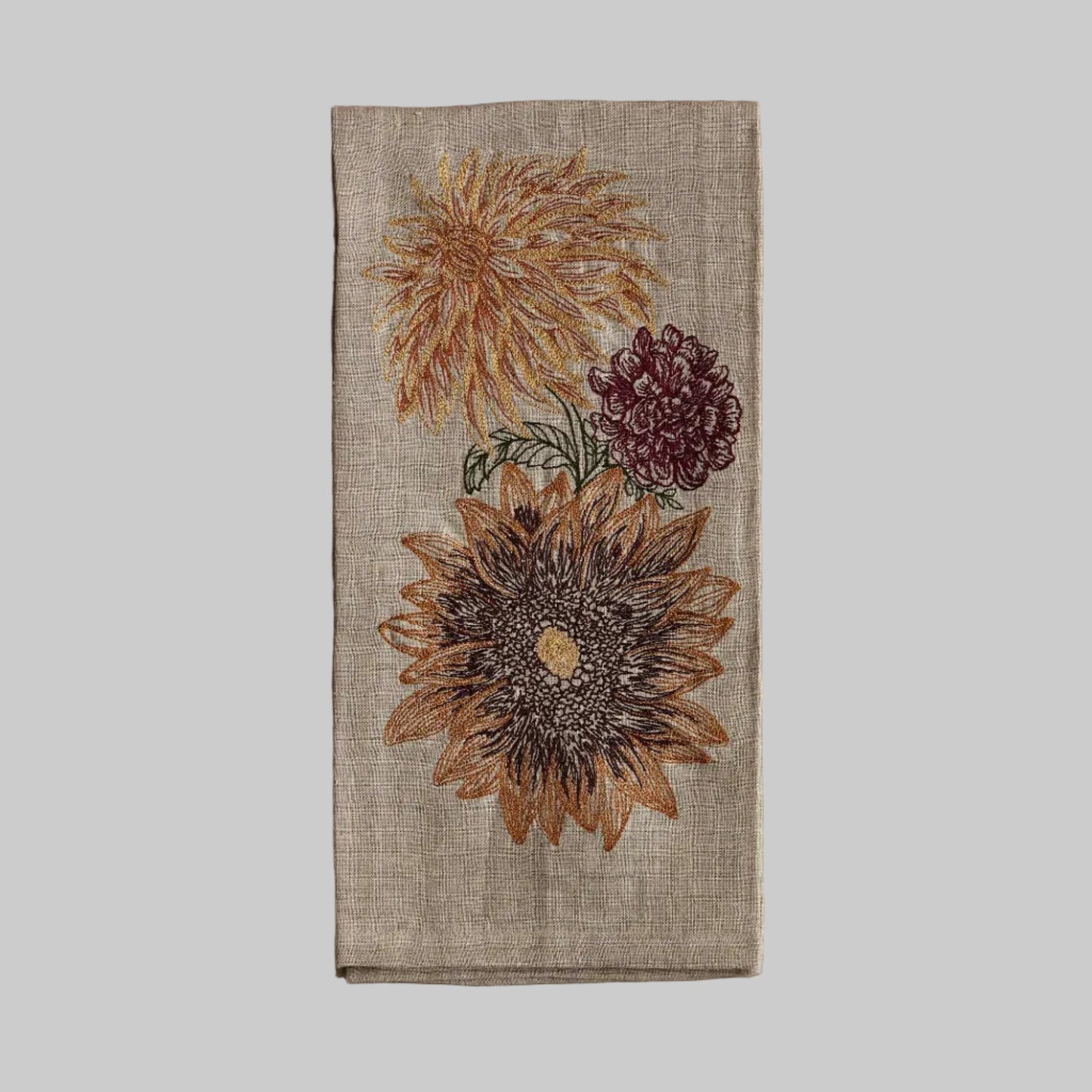 Coral and Tusk’s “Autumn Sunflower” embroidered linen tea towel featuring flower blooms in earthy tones