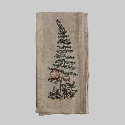 Coral and Tusk’s “Sword Fern” embroidered linen tea towel featuring small brown mushrooms in front of a fern frond