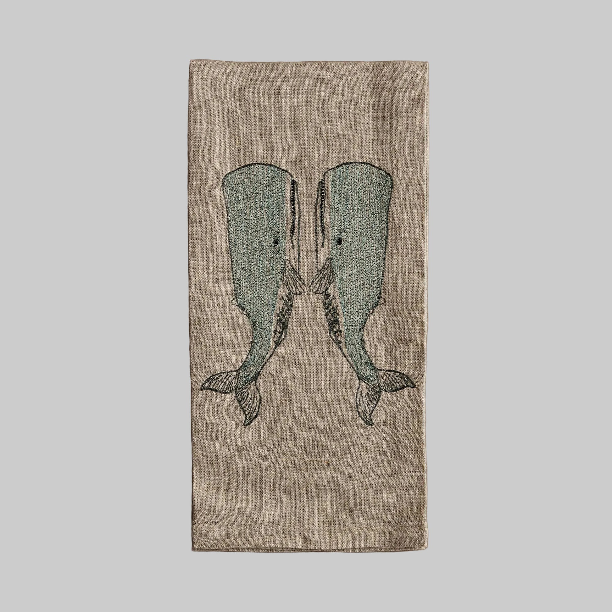 Coral and Tusk’s “Whale Love” embroidered linen tea towel featuring two whales holding fins