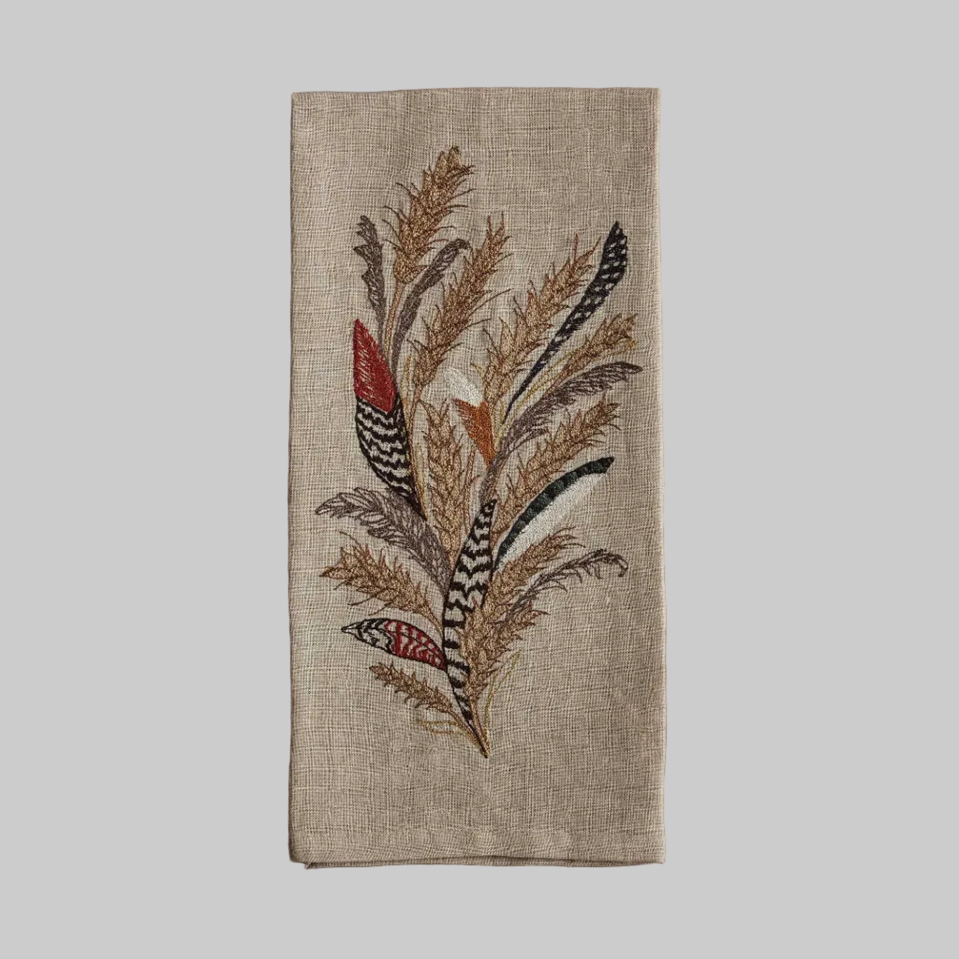 Coral and Tusk’s “Wheat Harvest” embroidered linen tea towel featuring a bouquet of wheat, grass, and found feathers